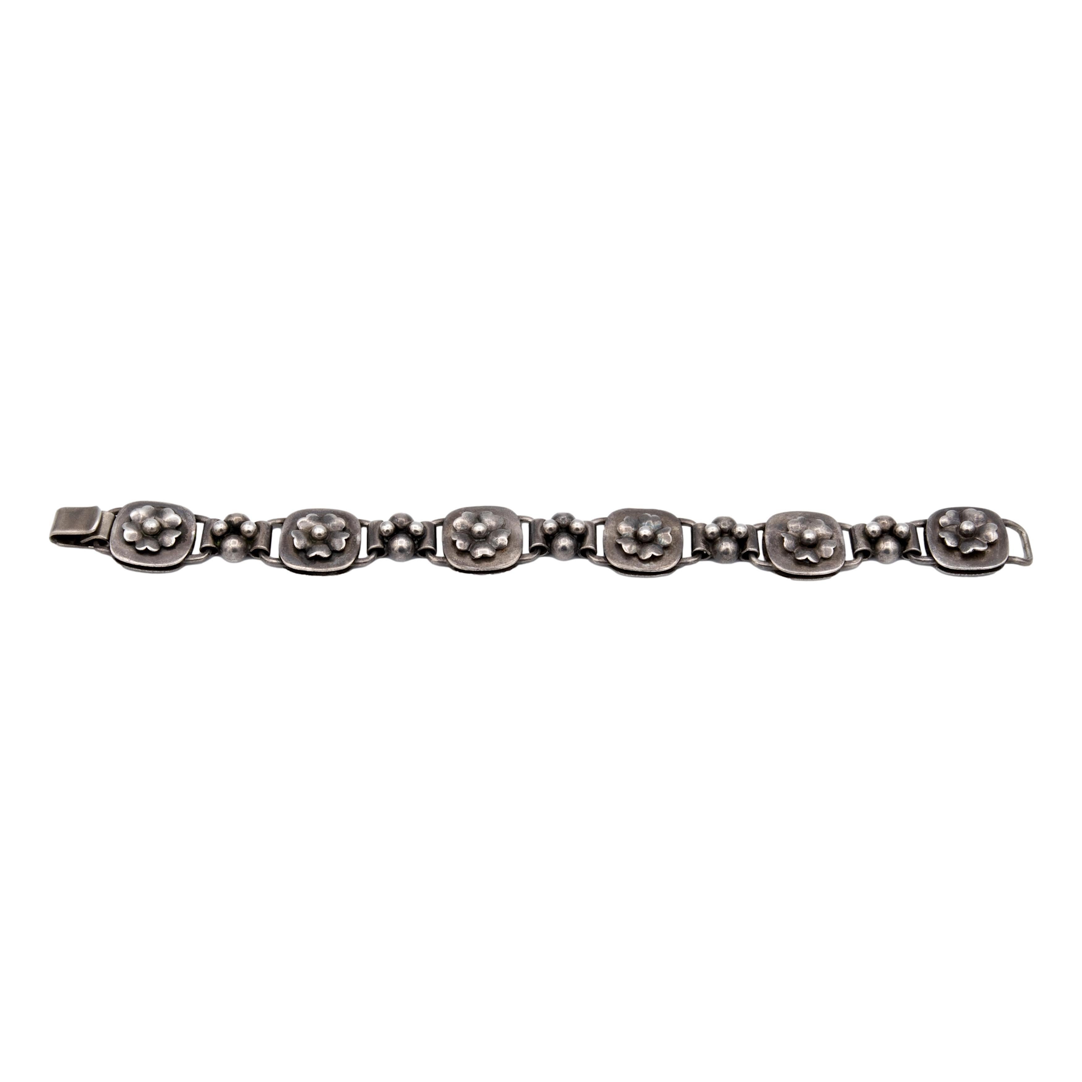 Vintage Georg Jensen bracelet, a sterling silver masterpiece featuring six exquisite floral motif sections with a slide hook lock mechanism. Georg Jensen's renowned craftsmanship shines through in this piece, reflecting his legacy of high-quality