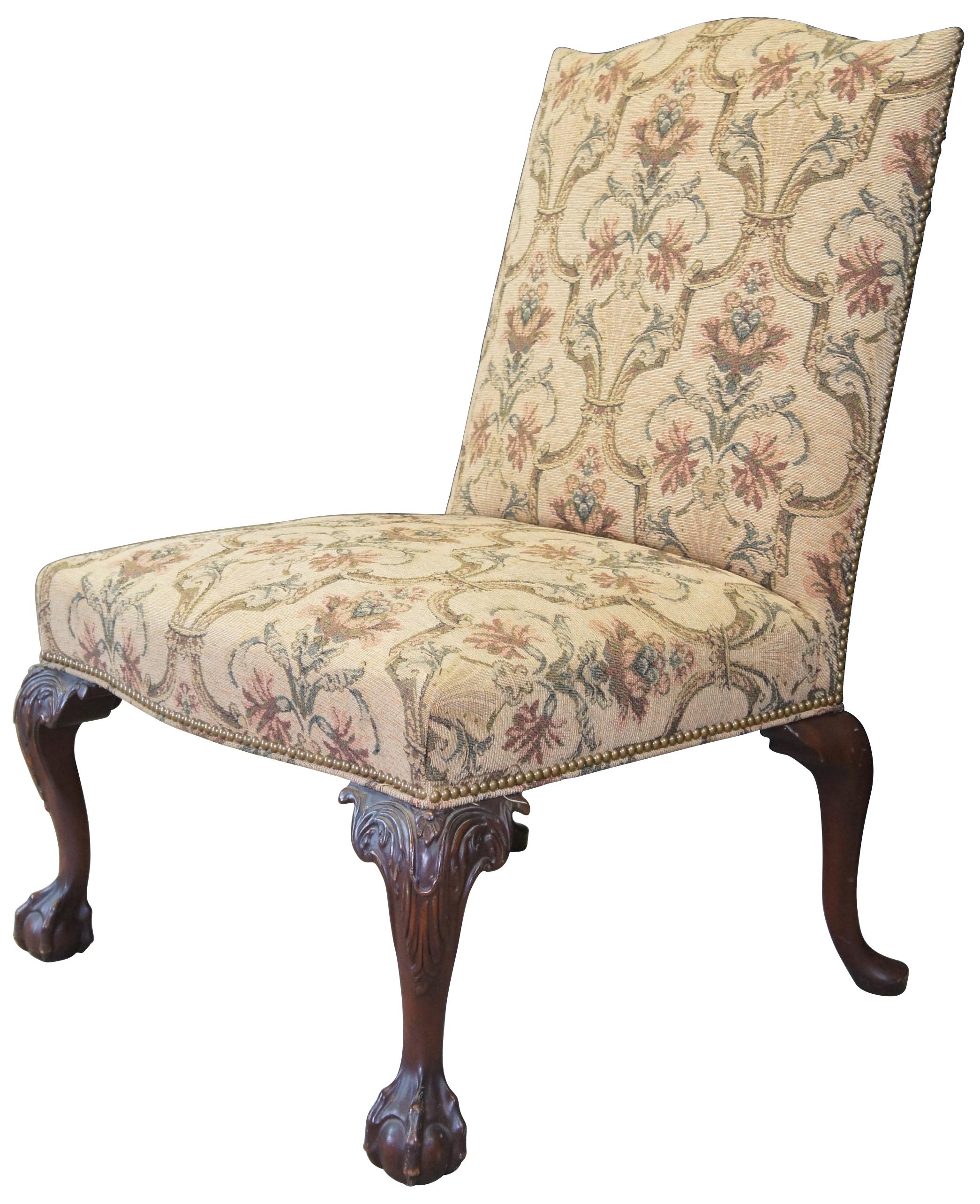 An impressive 20th century George II style library chair. Made from mahogany with a French brocade fabric. Features a camelback seat crest and cabriole legs, acanthus carved along the knee terminating into a ball and claw along the front and pad