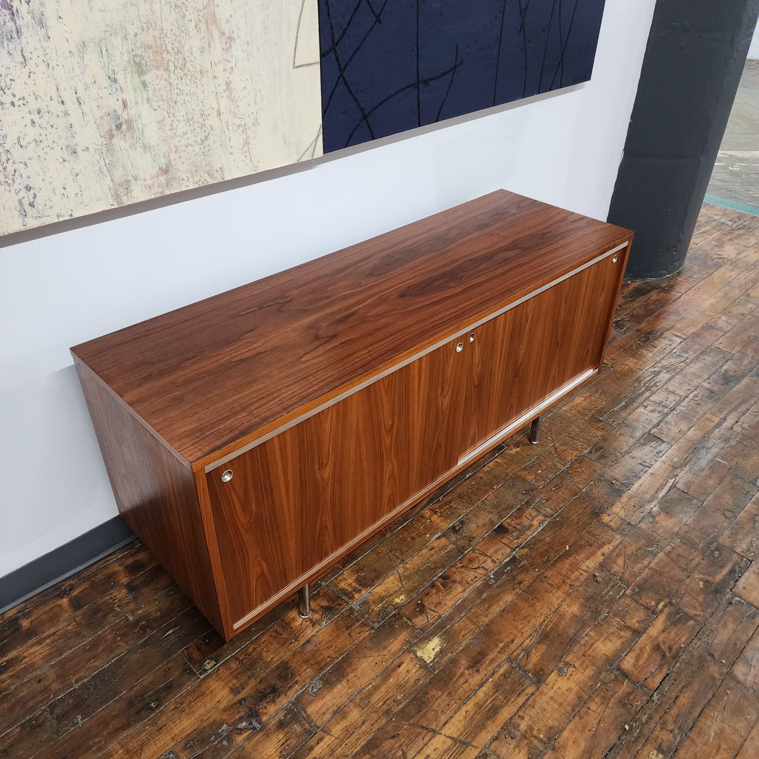 Beautiful Vintage George Nelson for Herman Miller Series 8000 Walnut Credenza. features chrome door glides with round chrome pulls and chrome legs. sliding walnut door with adjustable shelves inside. The back has been drilled for cable access.