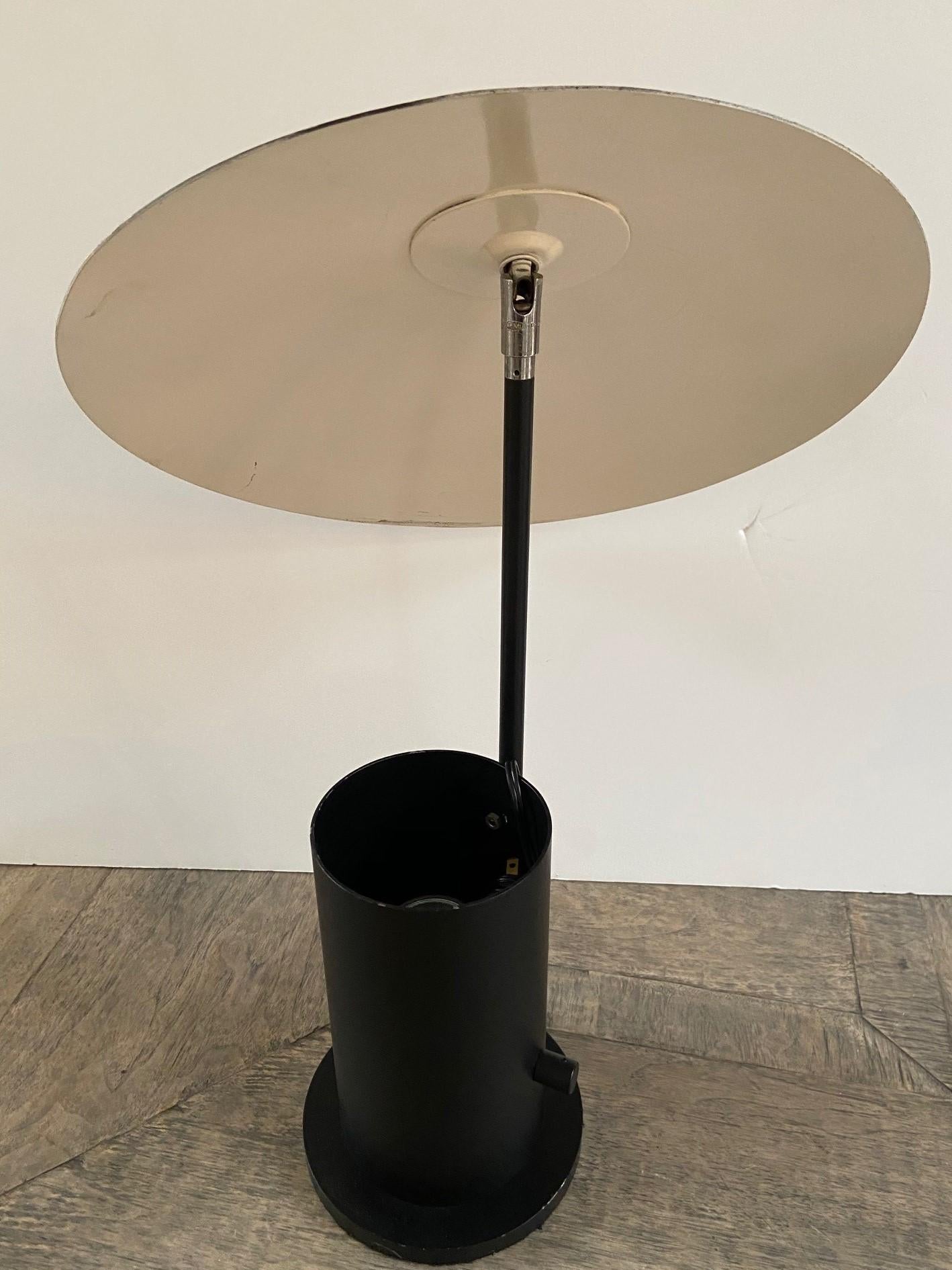 20th century enamel metal geometric modern table lamp, adjustable shade, light bulb sits in a cylindrical base design.