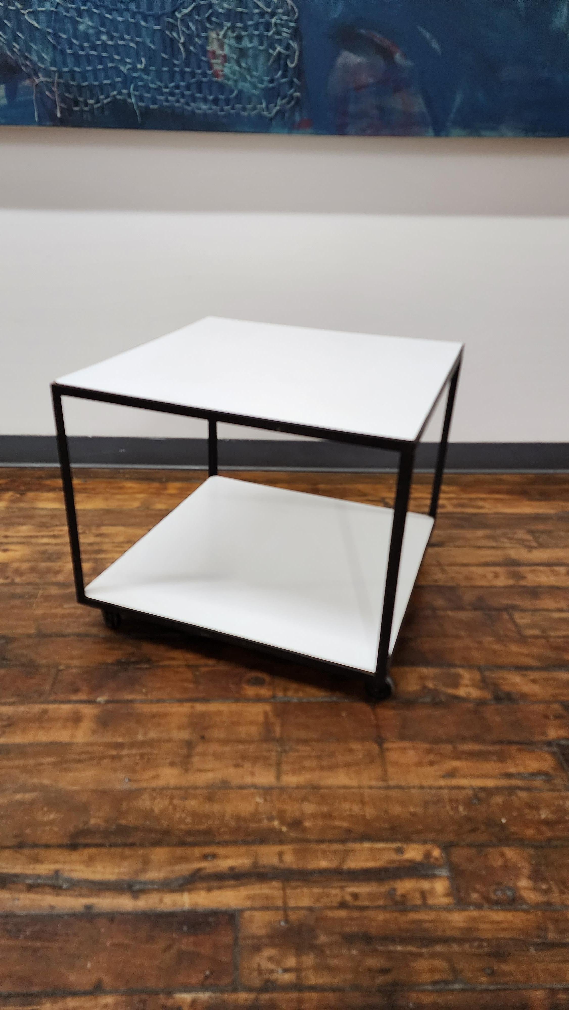 simple and elegant black steel frame with white laminate side table on castors. designed by George Nelson for Herman Miller