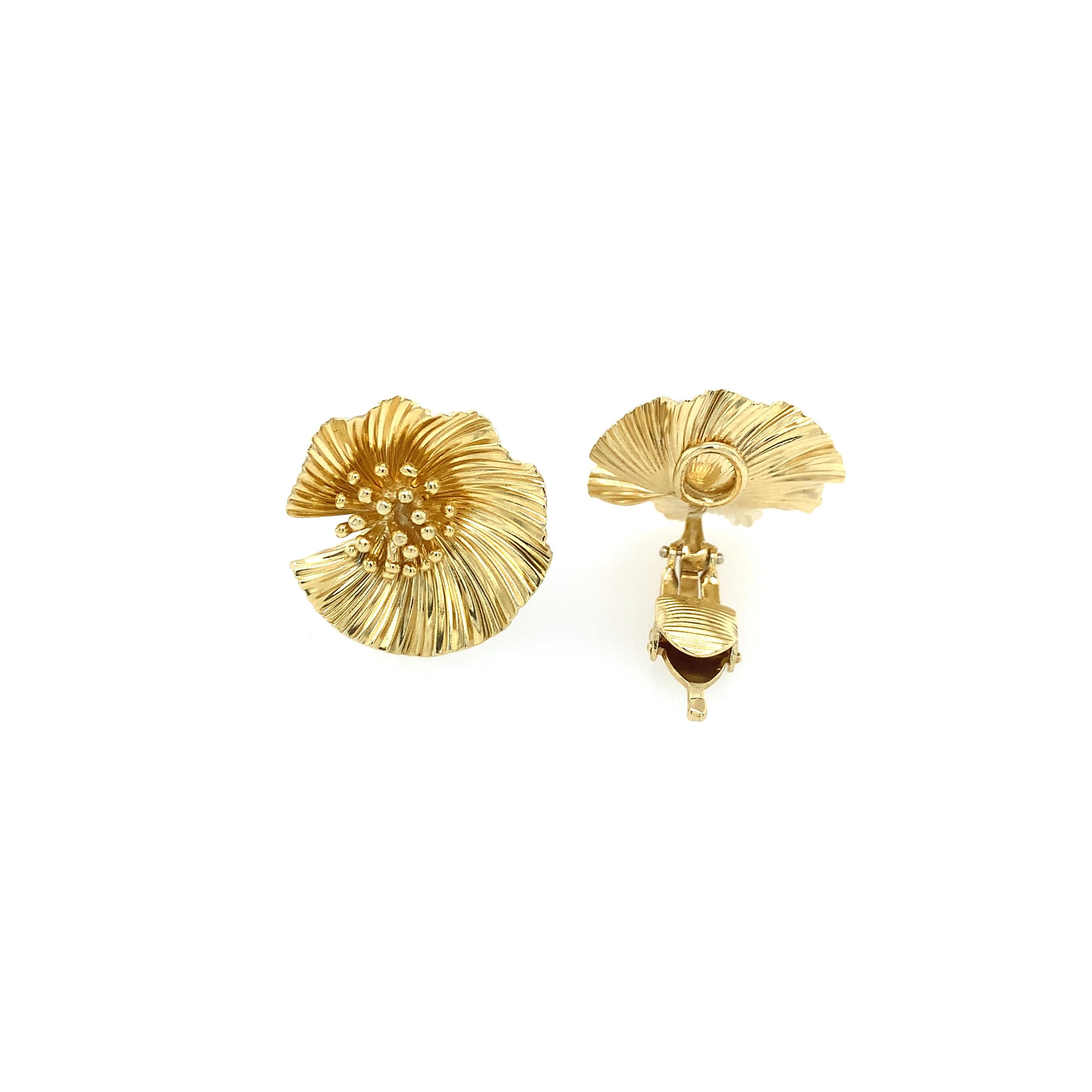 An iconic pair of 14K yellow gold earrings designed by George Schuler for McTeigue (Performed Parts). The prominent ruffled flowers are delicate in design, yet eye-catching with a textured life-like look. They feature comfortable clip backs which