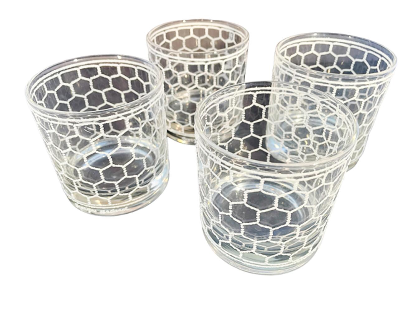 Four signed Georges Briard rocks glasses in clear glass with raised, textured white enamel design patterned after wire screening.