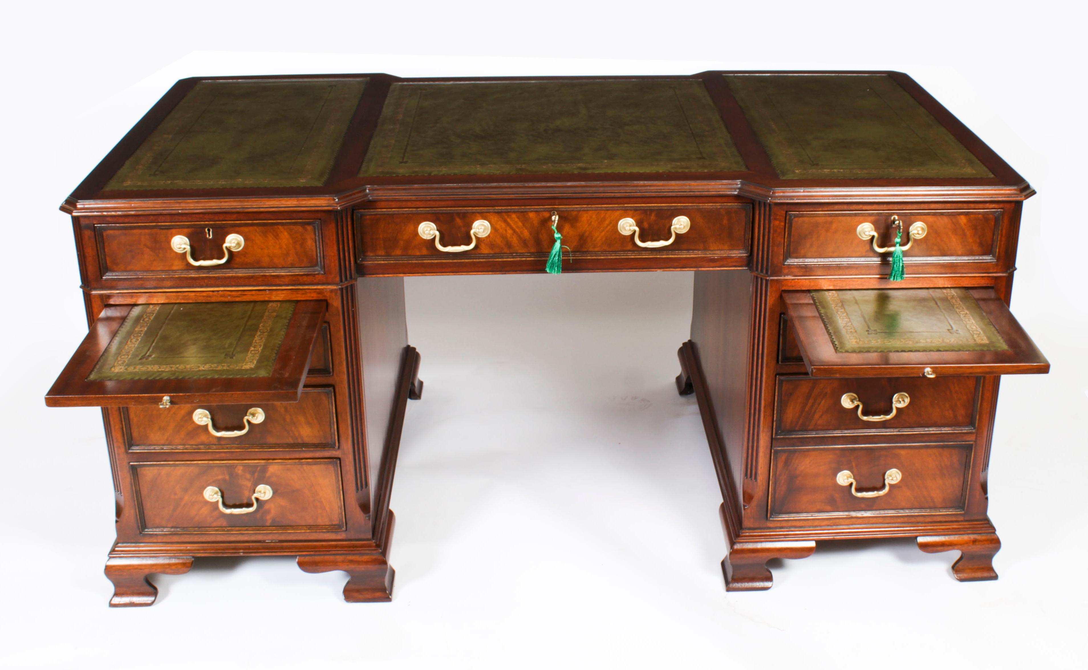 This is a stunning vintage Georgian Revival pedestal desk, masterfully crafted in flame mahogany, dating from the mid 20th century.

The desk top is of breakfront outline and is fiited with a beautiful inset three part gilt tooled green leather