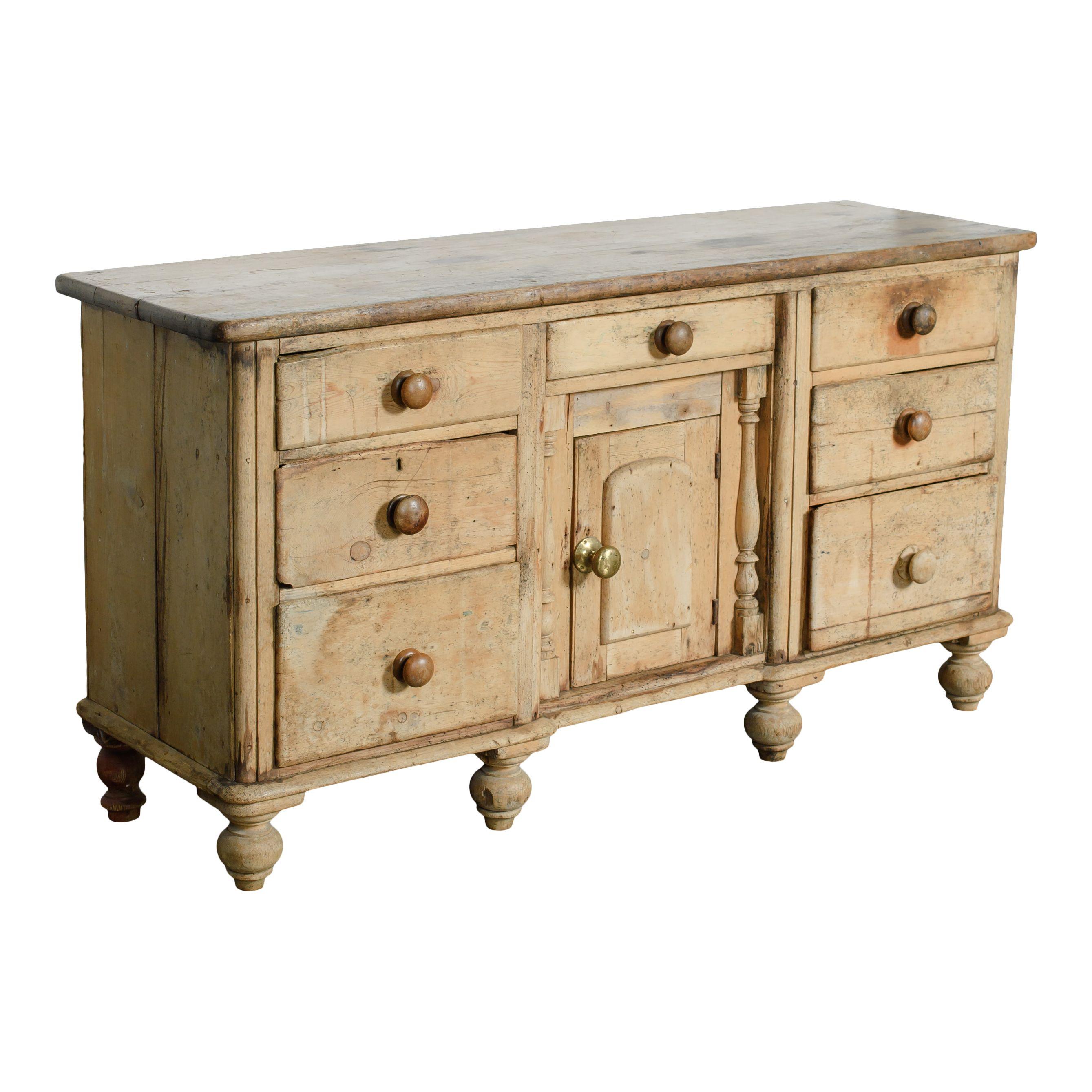 A beautifully simple sideboard made of wood. There are beautiful carved details and legs that give it so much character. The light wood also adds to its vintage charm. There are three drawers on each side and a cabinet with a shelf and one more