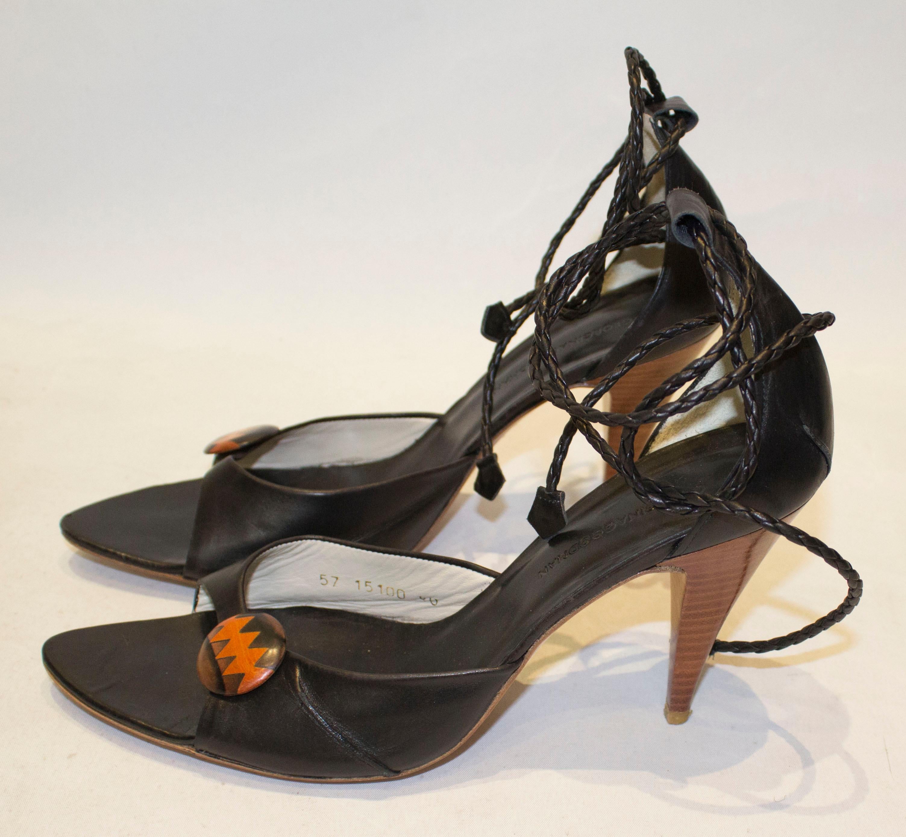 A chic pair of shoes from British designer Georgina Goodman.  The shoes have  black leather uppers with leather plait ankle ties, and a decorative button detail. The shoes have leather soles , and the heel height is 4 1/4''.