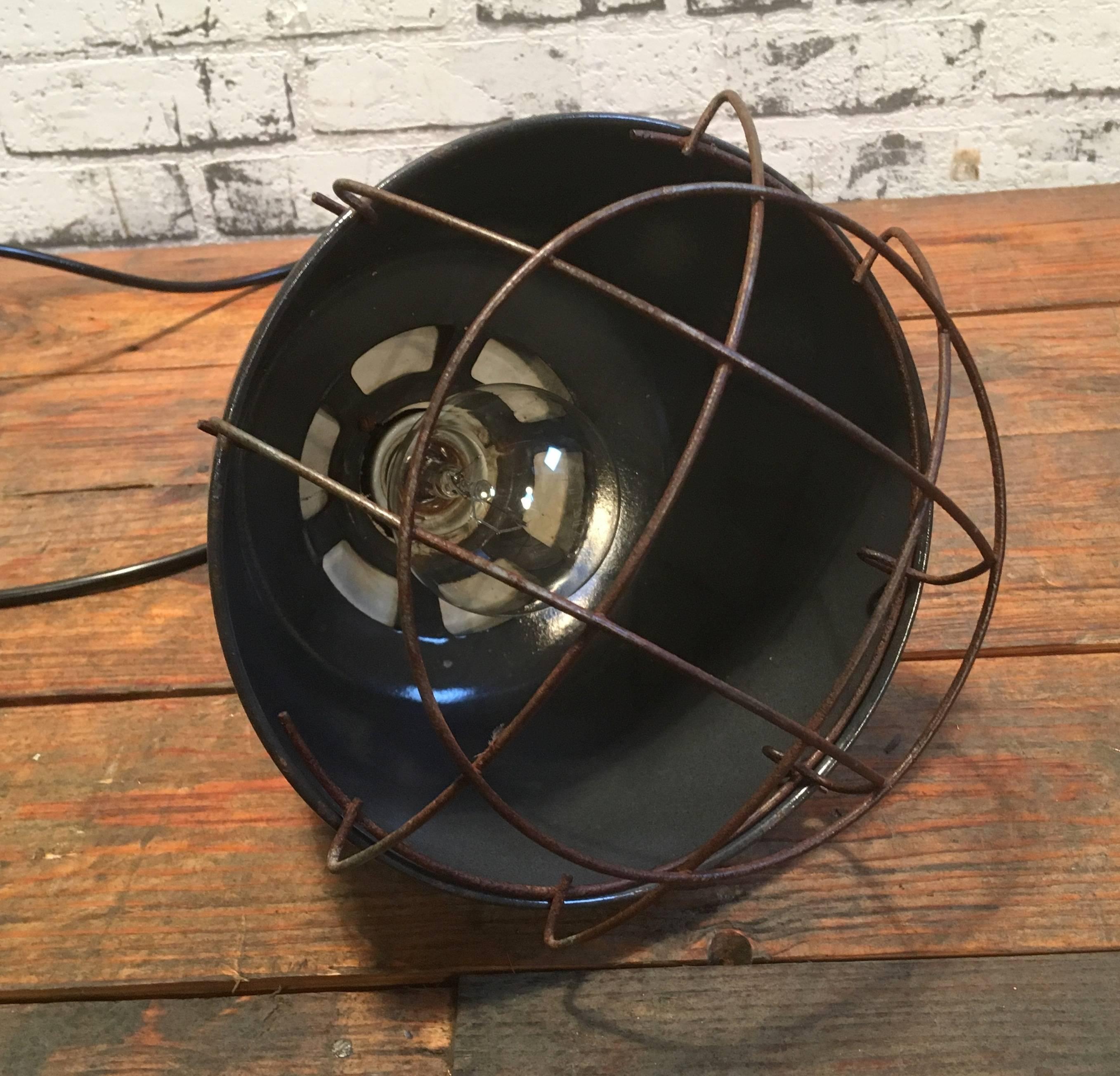 East German barn lamp, used mainly to warm up new born animals on the farm. 
Lamp has grey enemal metal body and bakelite dome. Iron cage. 
Porcelain socket for E27 bulbs. Newly wired.