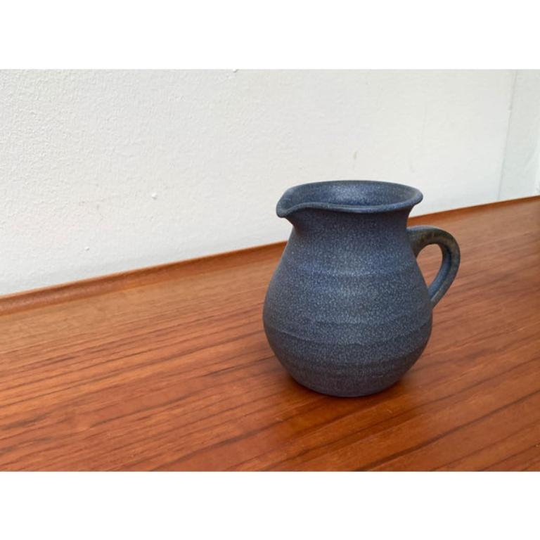 Vintage German Blue Ceramic Jug, 1970, en très bon état. Conçu de 1970 à 1979.

Informations complémentaires :
Matériaux : Céramique
Pays d'origine : Allemagne
Couleur : Bleu
Type d'article : Vintage, antique ou d'occasion
Dimensions : 5,51ʺW ×