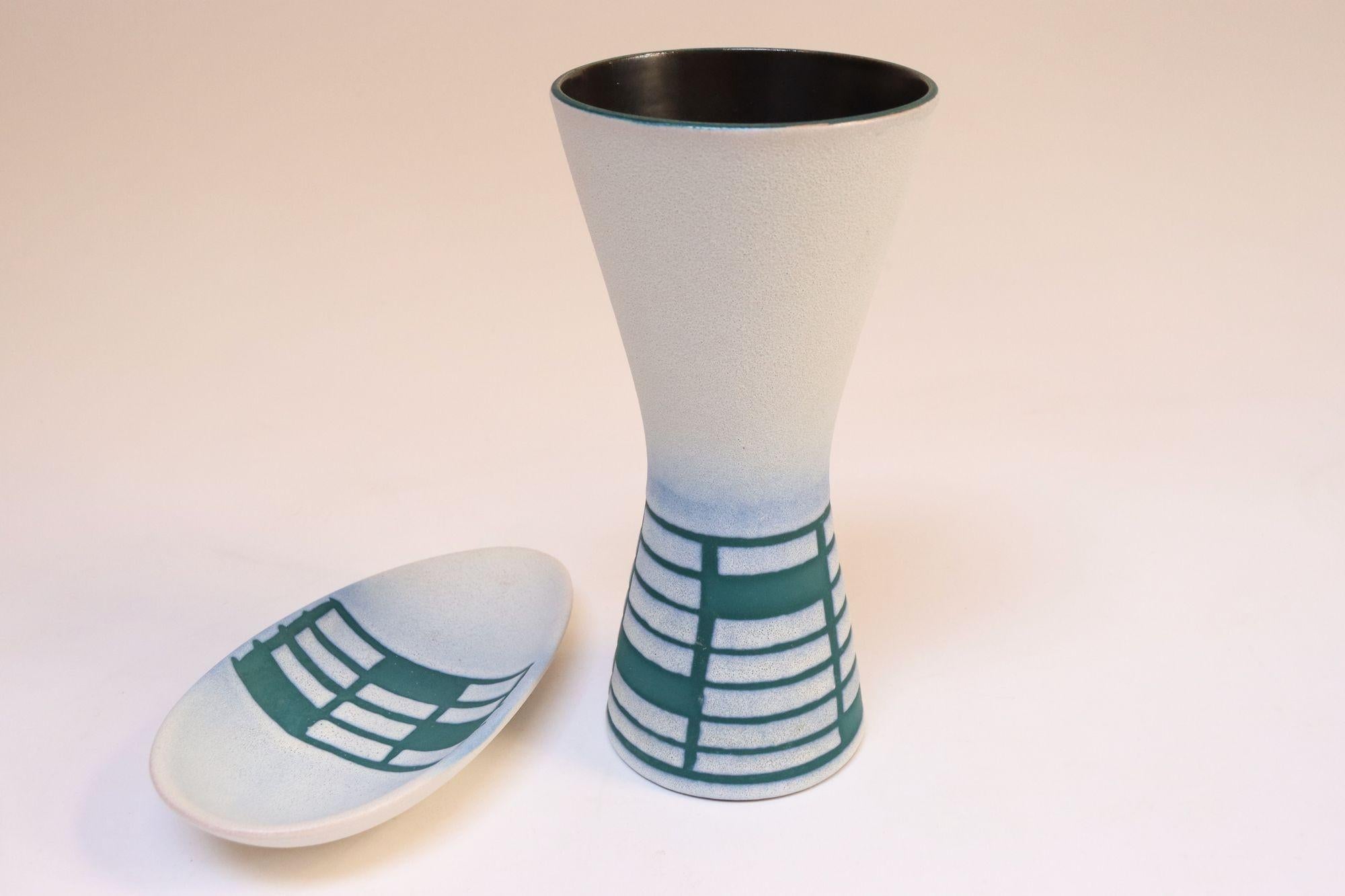 Steuler Keramik Vase in Diabolo-/Stundenglasform und tropfenförmige Schale (ca. 1970er Jahre, Deutschland).
Sie weisen ein geometrisches Muster aus Rechtecken in mattem Teal und Weiß auf (die Bereiche, in denen Teal die Grundfarbe ist, verleihen der
