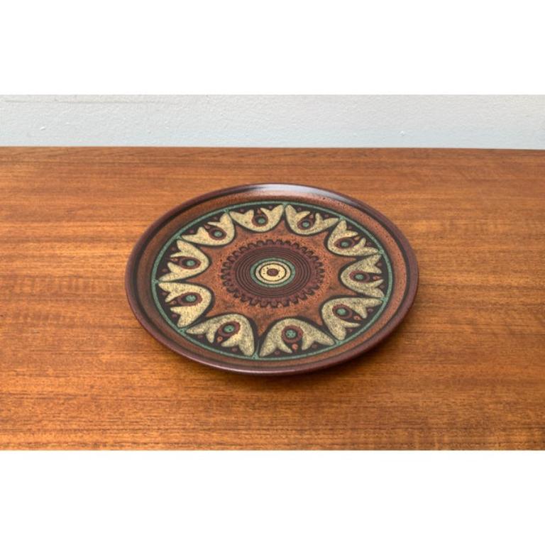 Vintage German Ceramic Wall Plate von Keramik Manufaktur Kupfermühle, 1970er Jahre, in sehr gutem Zustand. Entworfen 1970 bis 1979 offizieller Echtheitsnachweis wie Vintage-Kataloge, Designer-Aufzeichnungen oder andere Literaturquellen.

Zusätzliche