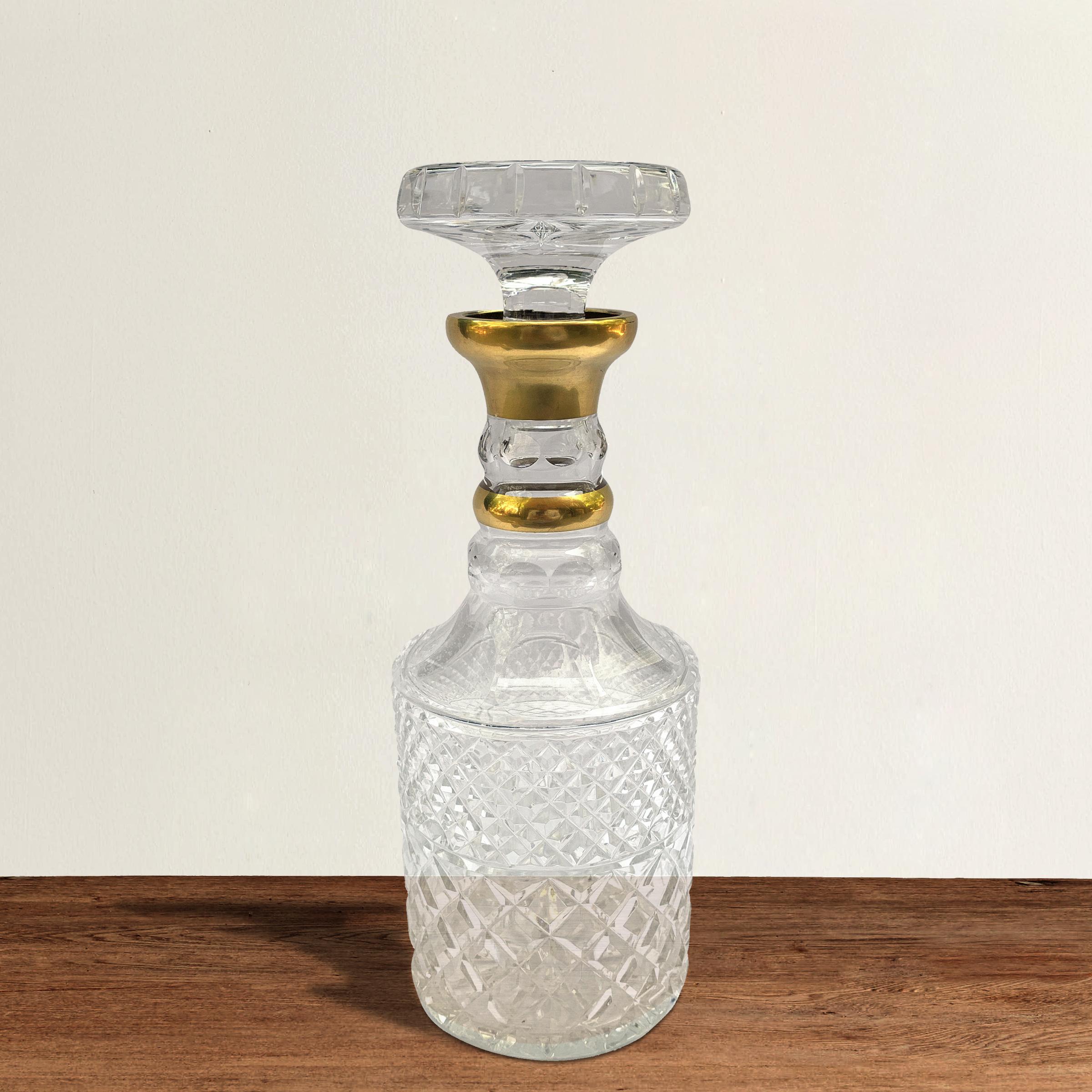 A beautiful mid-20th century German handcut crystal decanter with stopper, gilt details on the neck, and diamond cutting around the base. The top of the stopper and the foot are both cut with a star pattern.