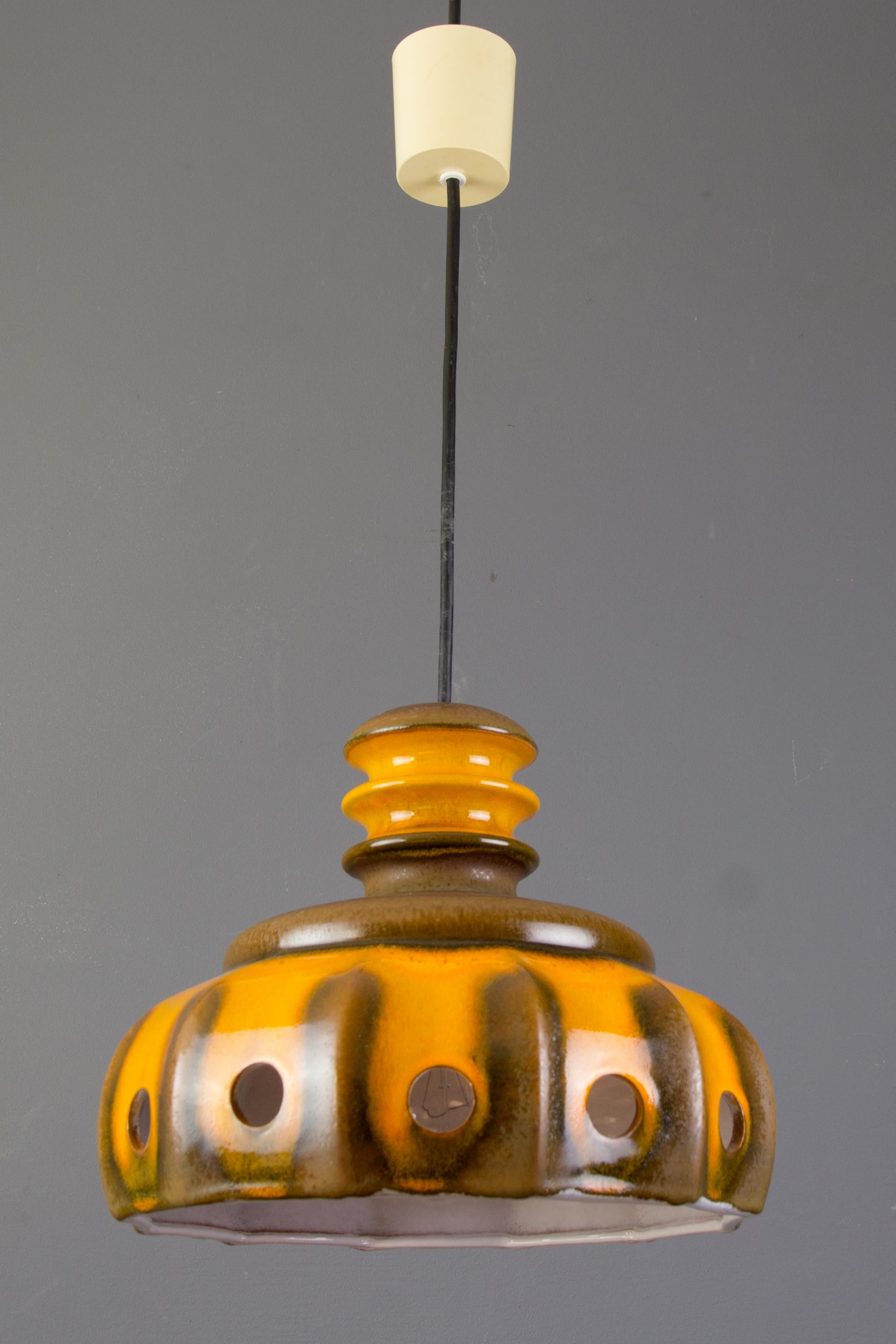 Colorful orange and brown German ceramic Fat Lava or West German Pottery pendant ceiling light, glazed outside and inside. The light comes through the circles creating wonderful shadows upon the wall. Adjustable height and one socket for E27 light