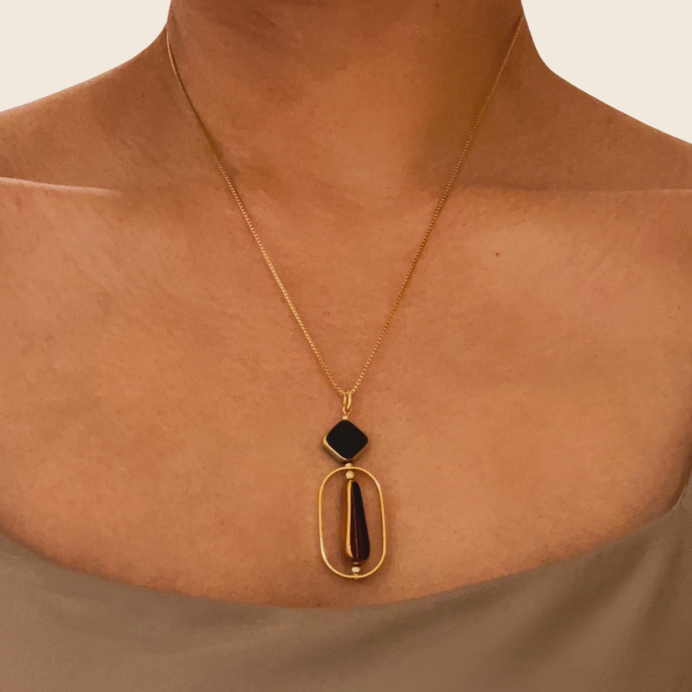 Le pendentif est composé de perles noires en forme de diamant et de perles bordeaux en verre allemand vintage en forme de goutte d'eau. Il est terminé par une chaîne de 18 pouces en or.

Les perles sont de nouvelles perles de verre allemandes