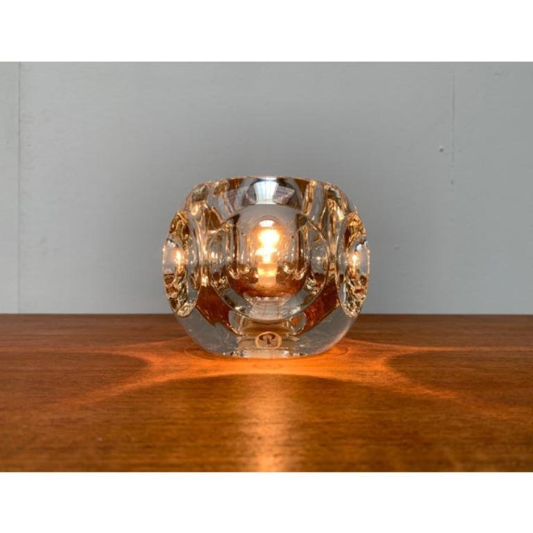 Lampada da tavolo in vetro del rinomato produttore Peill & Putzler.

Il corpo della lampada, di forma esagonale, è realizzato in spesso vetro trasparente. Le superfici laterali sono concave e rientranti. Il materiale rifrange e diffonde la luce,
