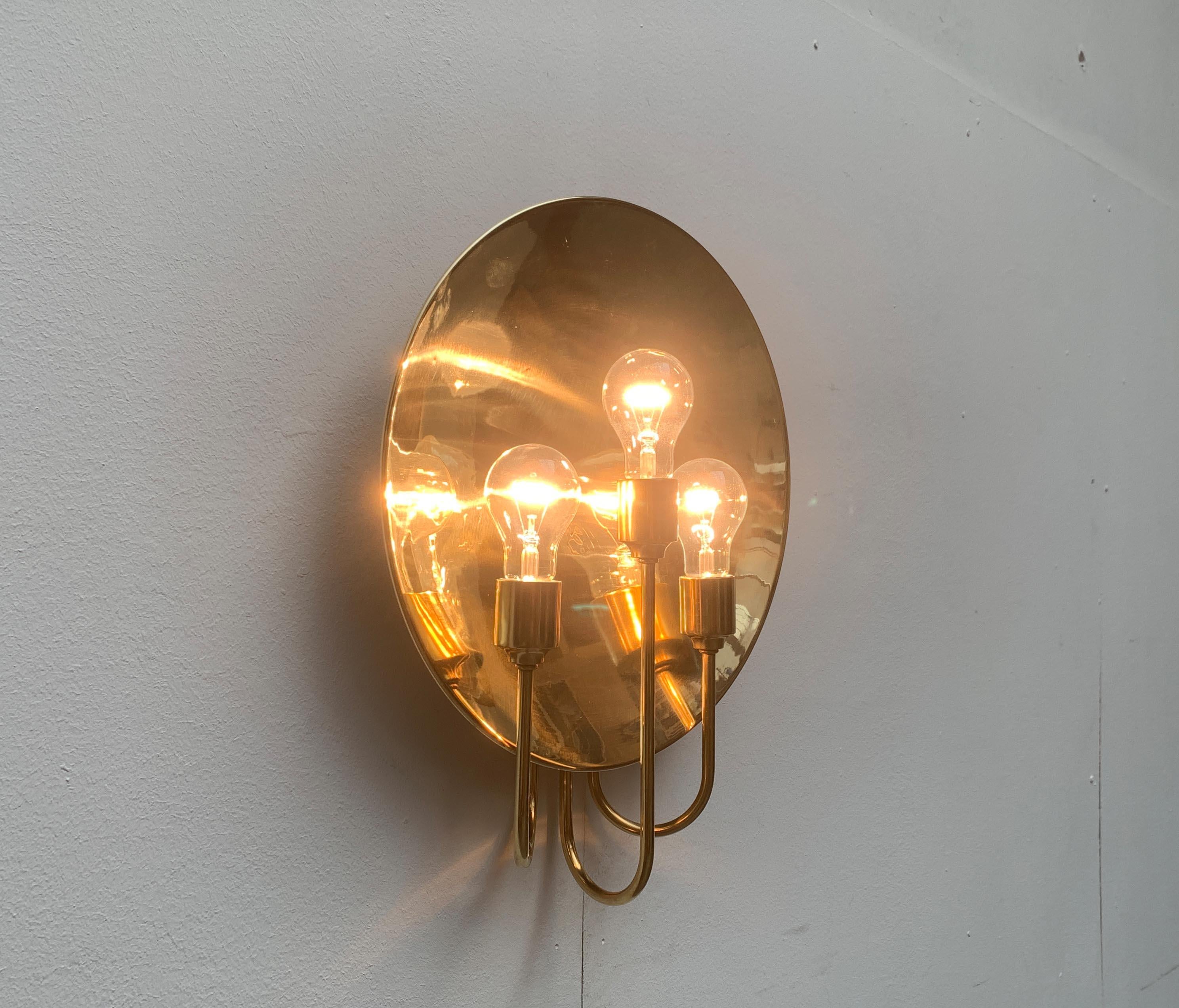 Impresionante aplique del diseñador de lámparas Florian Schulz.

El diseño convence por su sencilla elegancia y su materialidad de alta calidad. Las tres tomas se asientan sobre brazos elegantemente curvados delante de un gran disco reflector. El