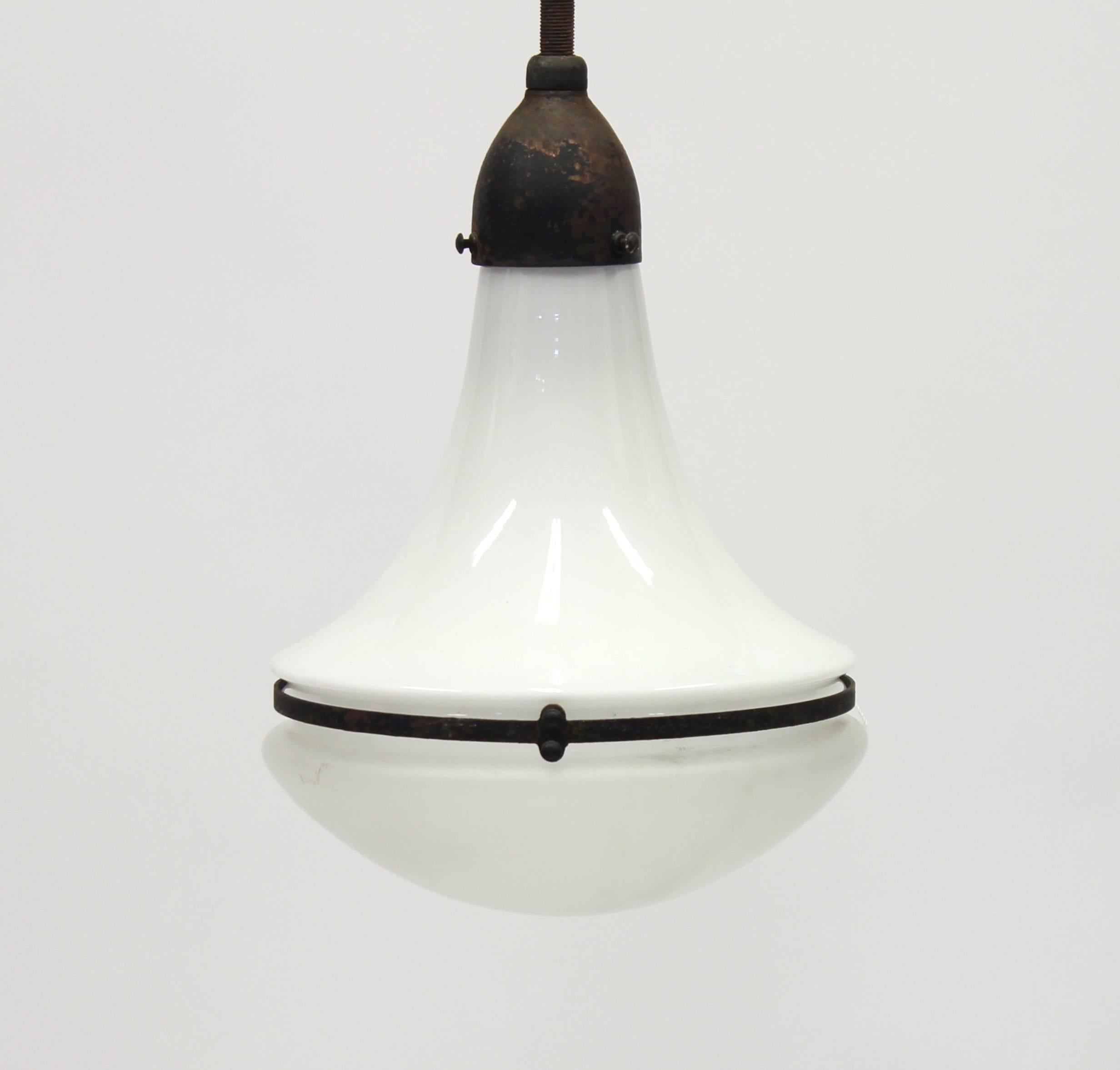 This Peter Behrens design piece from circa 1910 was manufactured in Germany by AEG. An opaline white glass shade is held in place by a bell-shaped metallic attachment and stem, encasing the bulb for the diffusion of the light. The referred height