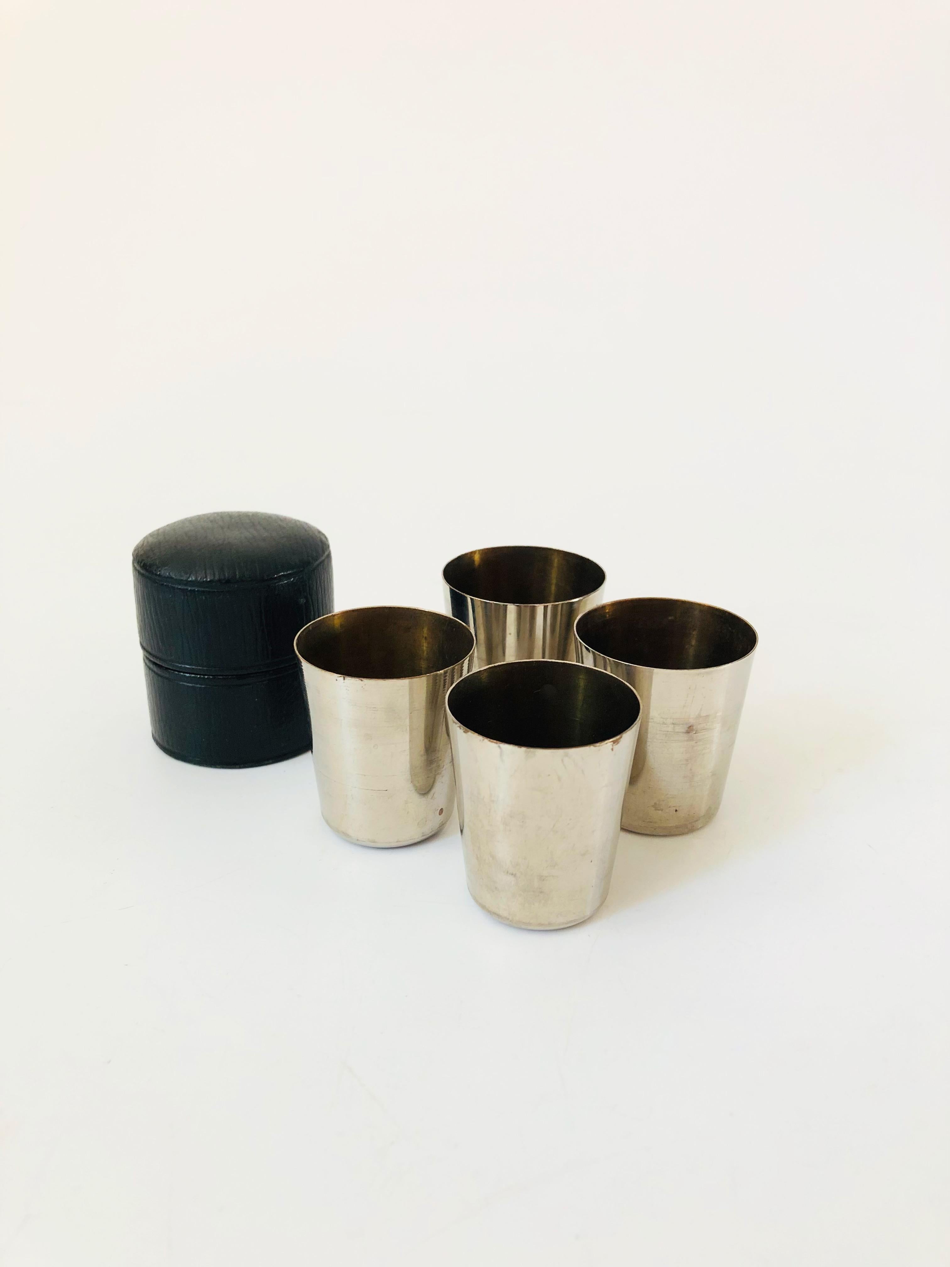 A set of 4 vintage German metal shot glasses in a faux leather case. Each shotglass is made of silver tone metal with a bright gold interior. The stack neatly into each other for storage and within the case. Each cup is marked Germany on the