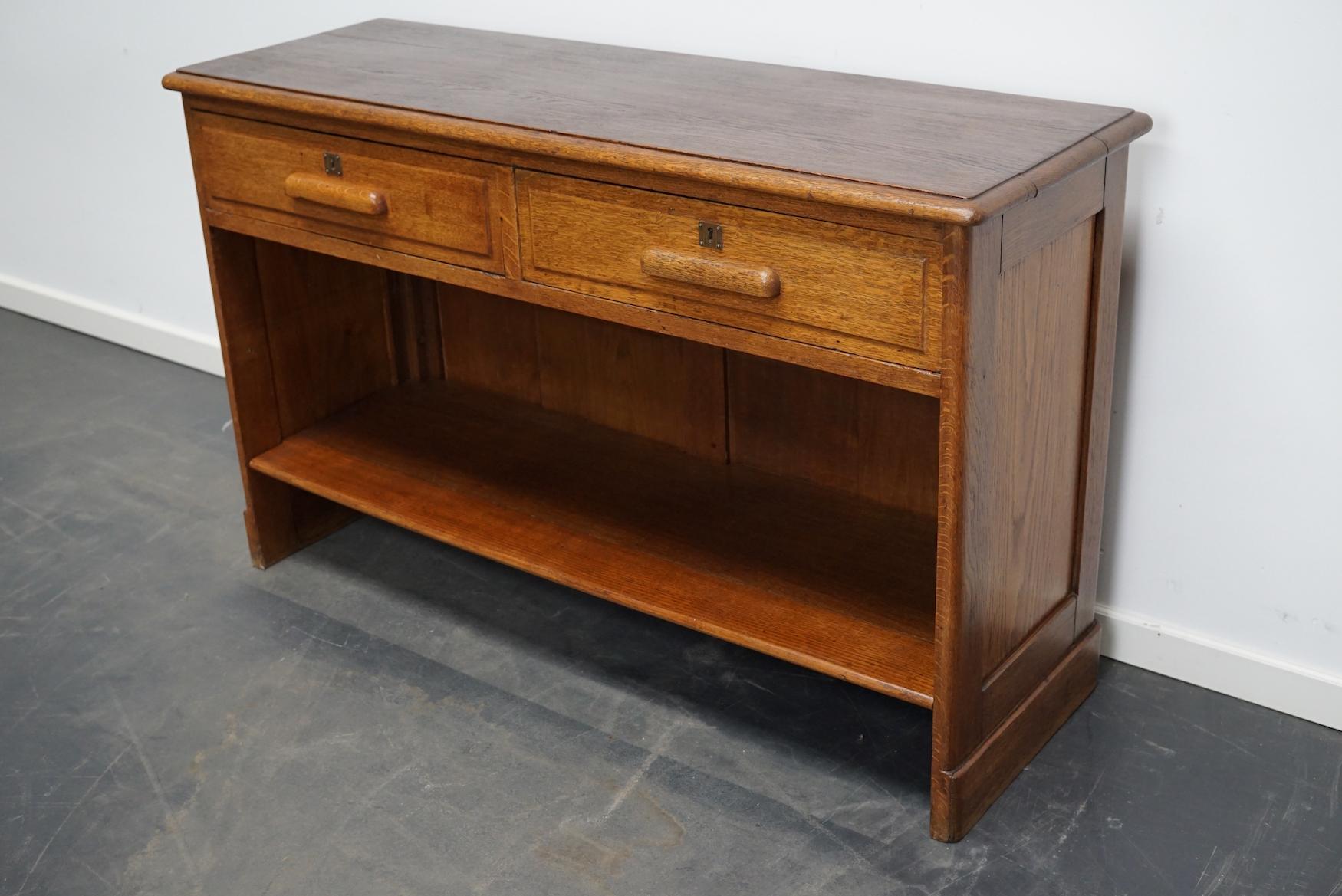 This oak shop counter was made around the 1930s in Germany. It was very well made and it remains in a good antique condition. The interior dimension of the drawers are: D W H 31 x 53 x 12 cm.