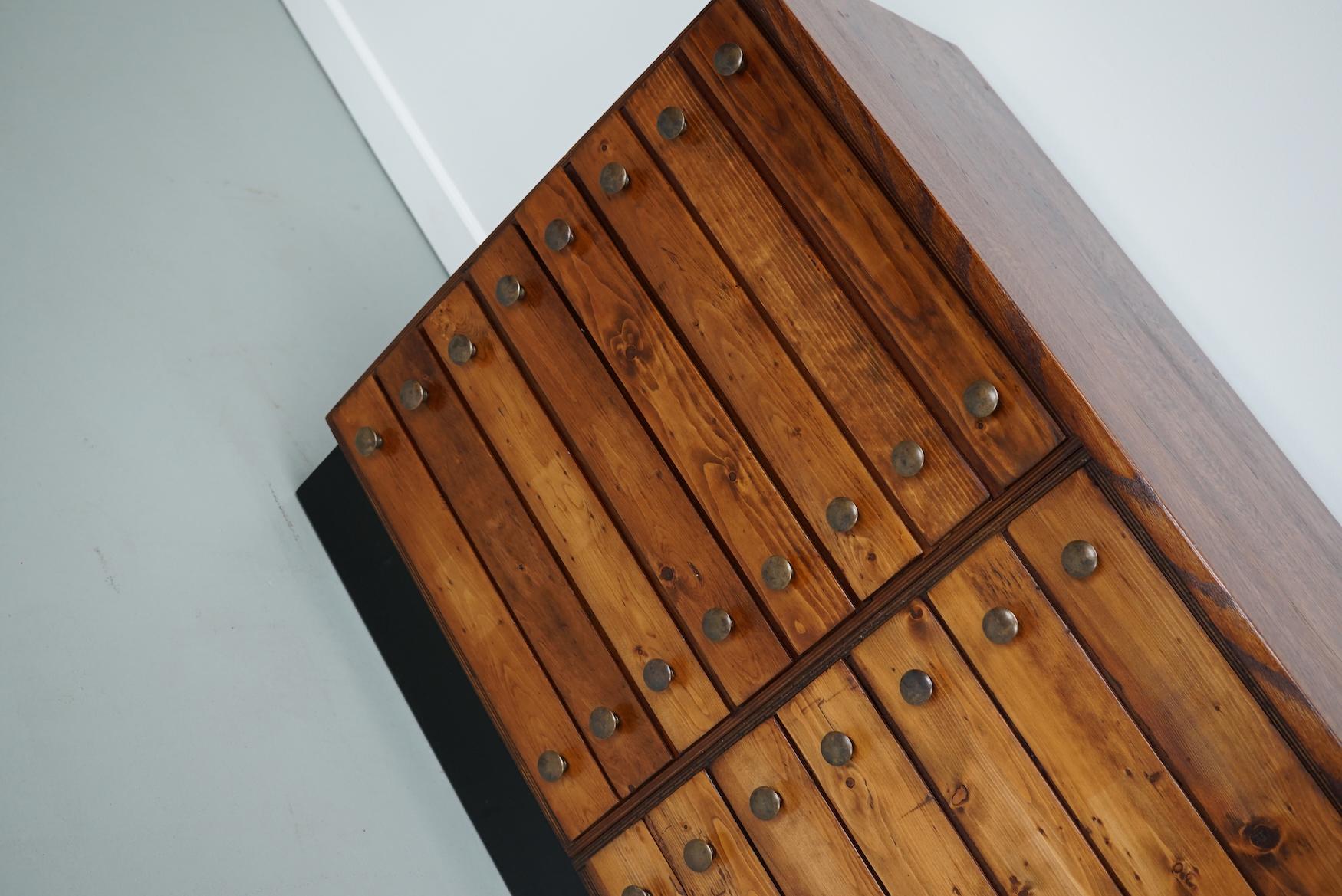 Dieser Apothekerschrank wurde in den 1950er Jahren in Deutschland hergestellt. Dieses Stück hat 23 Schubladen mit schönen Messingknöpfen. Die Innenmaße der Schubladen sind: D x B x H 42 x 43 x 4,5 cm. Es befindet sich in einem gut restaurierten