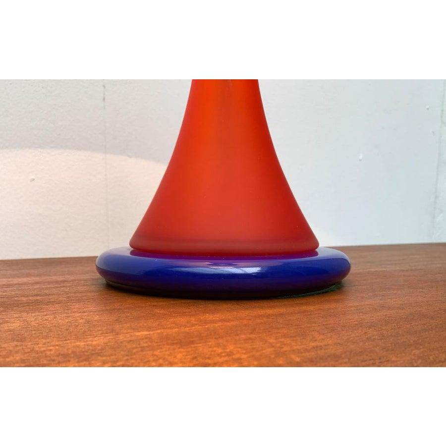 Table lamp from the German manufacturer Nachtmann, designed by Matteo Thun.

A draft in a postmodern design language. The classic luminaire shape meets bright color in the basic colors blue, red and yellow. The classic gold rim on the umbrella is