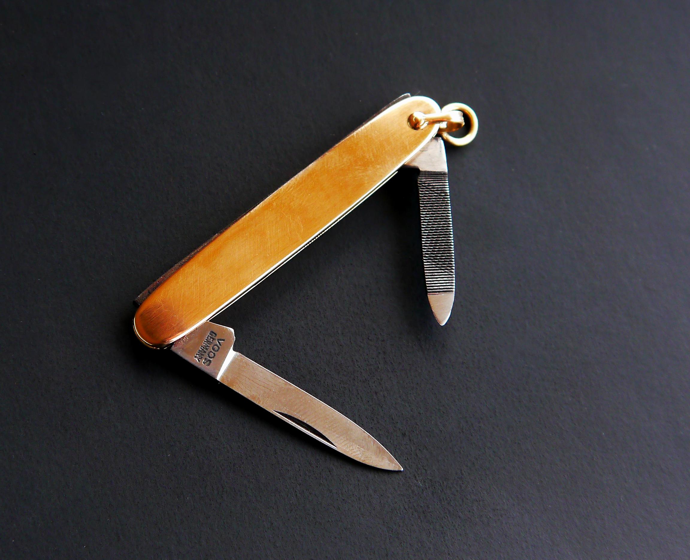 Taschenmesser mit faltbarer Klinge und Nagelfeile, mittelgroß.

Klinge und ein Teil des Rahmens sind aus Stahl, die beiden Seiten-/Handschalen sind aus massivem 14-karätigem Gelbgold gefertigt.


Die rostfreie Klinge ist mit dem Logo von Emil Voos,