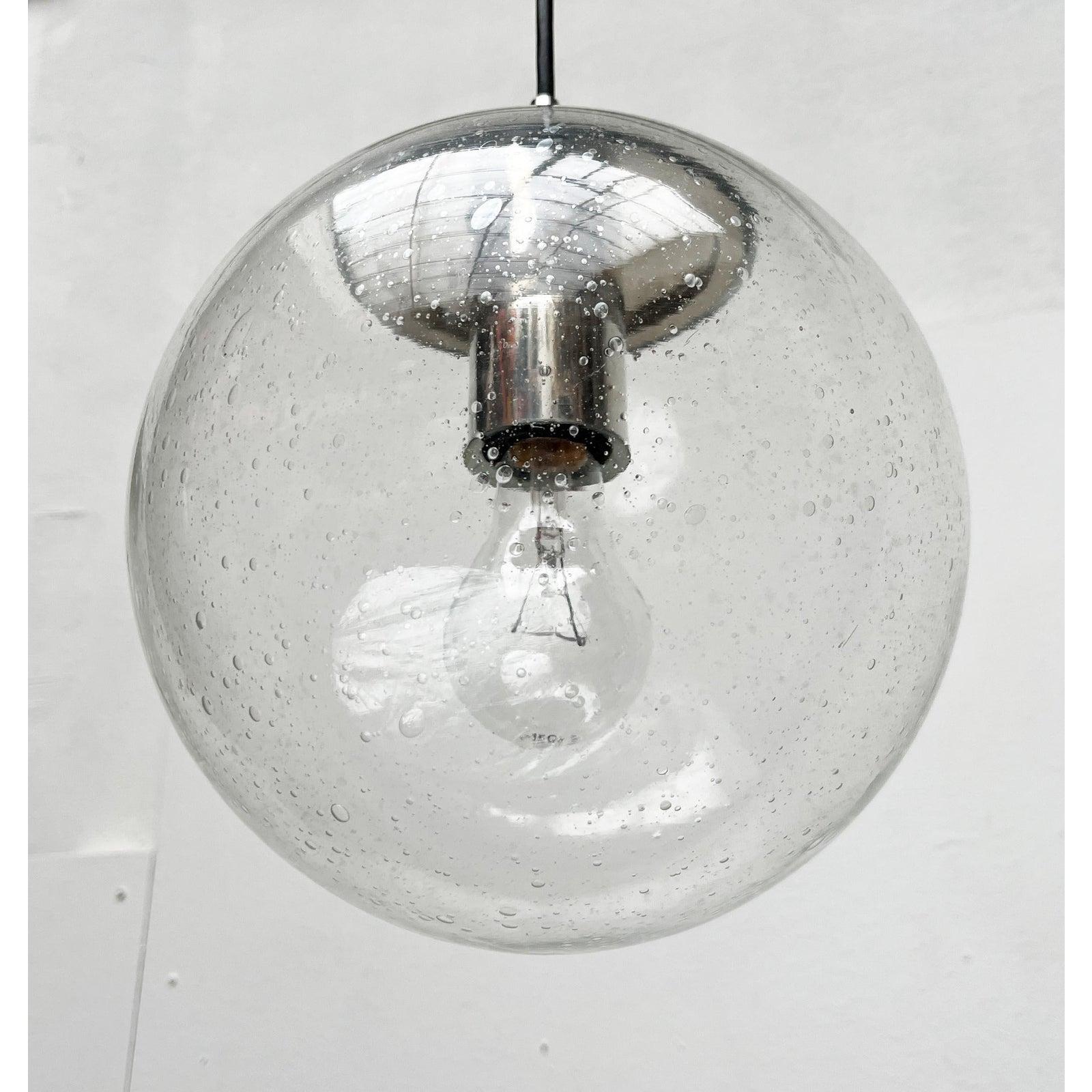 Glas-Pendelleuchte des renommierten Herstellers Peill & Putzler.

Eine klassische Kugel-Pendelleuchte. Der Lampenkörper ist aus klarem Glas mit Blasenstruktur gefertigt. Die Blasen im Glas setzen stimmungsvolle Lichtakzente. Der Beschlag ist