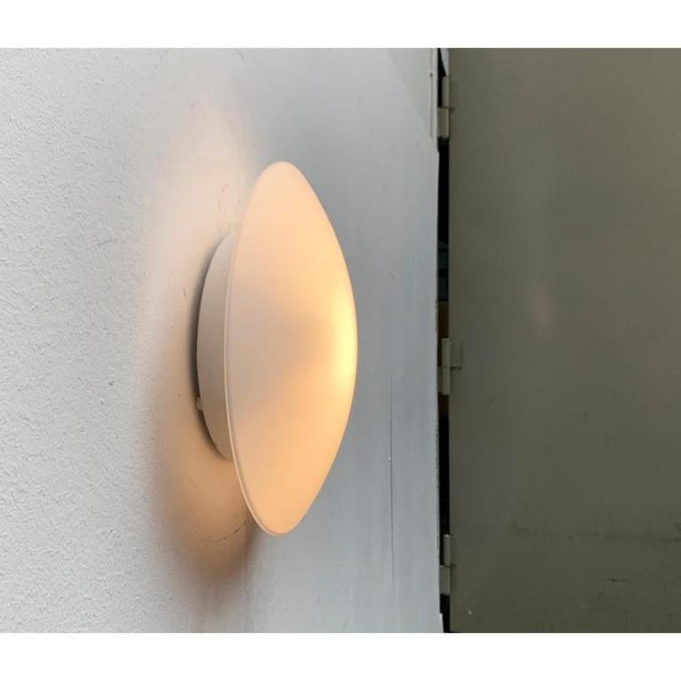 Applique ou plafonnier simple du célèbre fabricant cleaner.

La forme simple du diffuseur en verre opale attire particulièrement l'attention. Le verre coule vers le bord. Le diffuseur est séparé d'une large base de mur ou de plafond. Cette pièce
