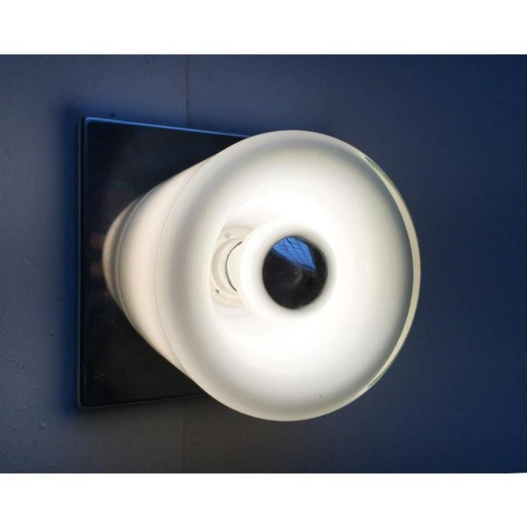 Imposante lampe murale NO AGE du célèbre fabricant Doria Leuchten.

Sur une plaque murale chromée carrée repose un corps cylindrique en verre. Le corps en verre sert à la fois de réflecteur et de diffuseur. La lumière directe émerge à l'avant. En
