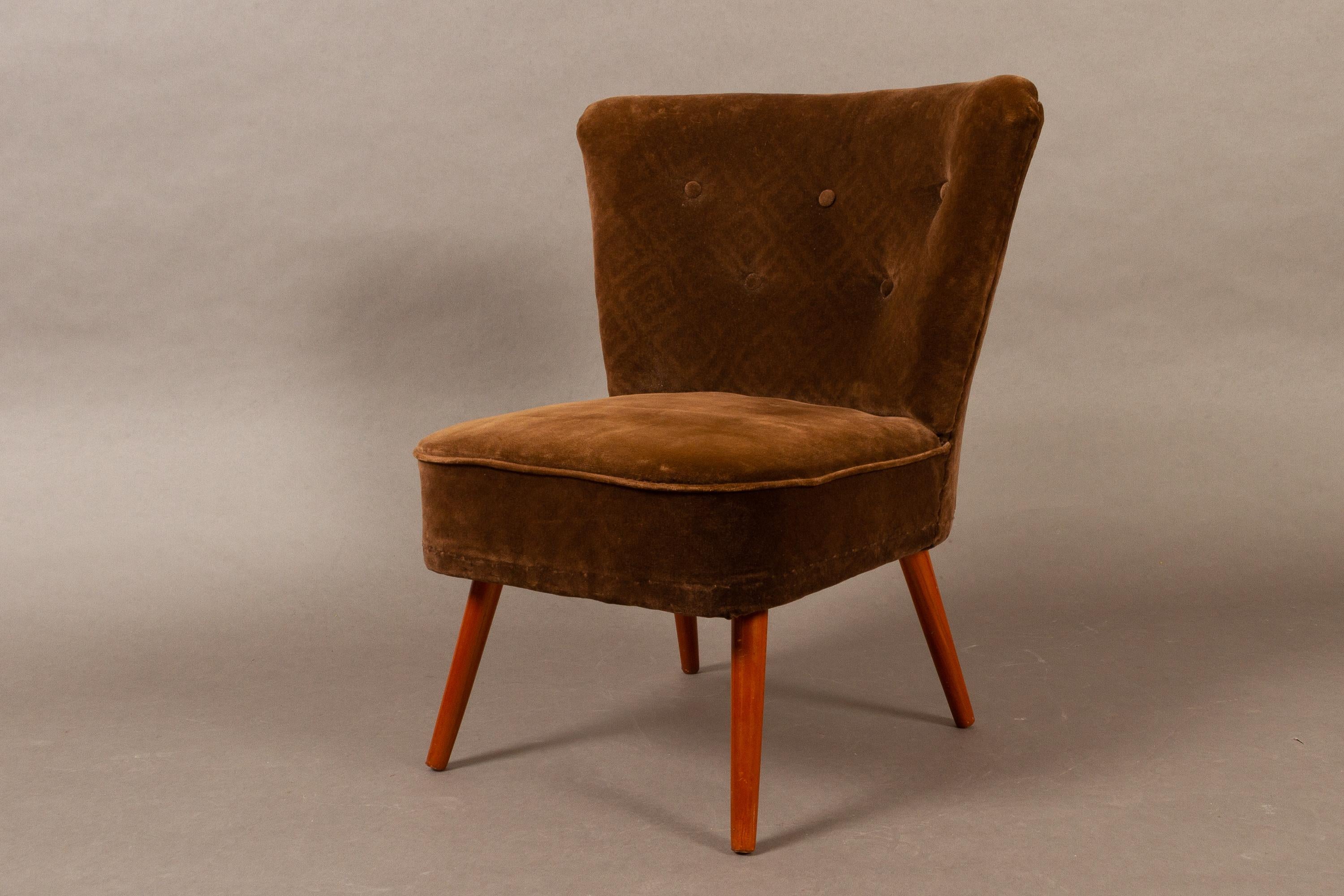 Vintage German velvet cocktail chair, 1960s.
Made by VEB Polstermöbelverkstätten Aue in former DDR.
Dark brown patterned velvet upholstery with buttons. Standing on round tapered legs in stained wood.

                  
