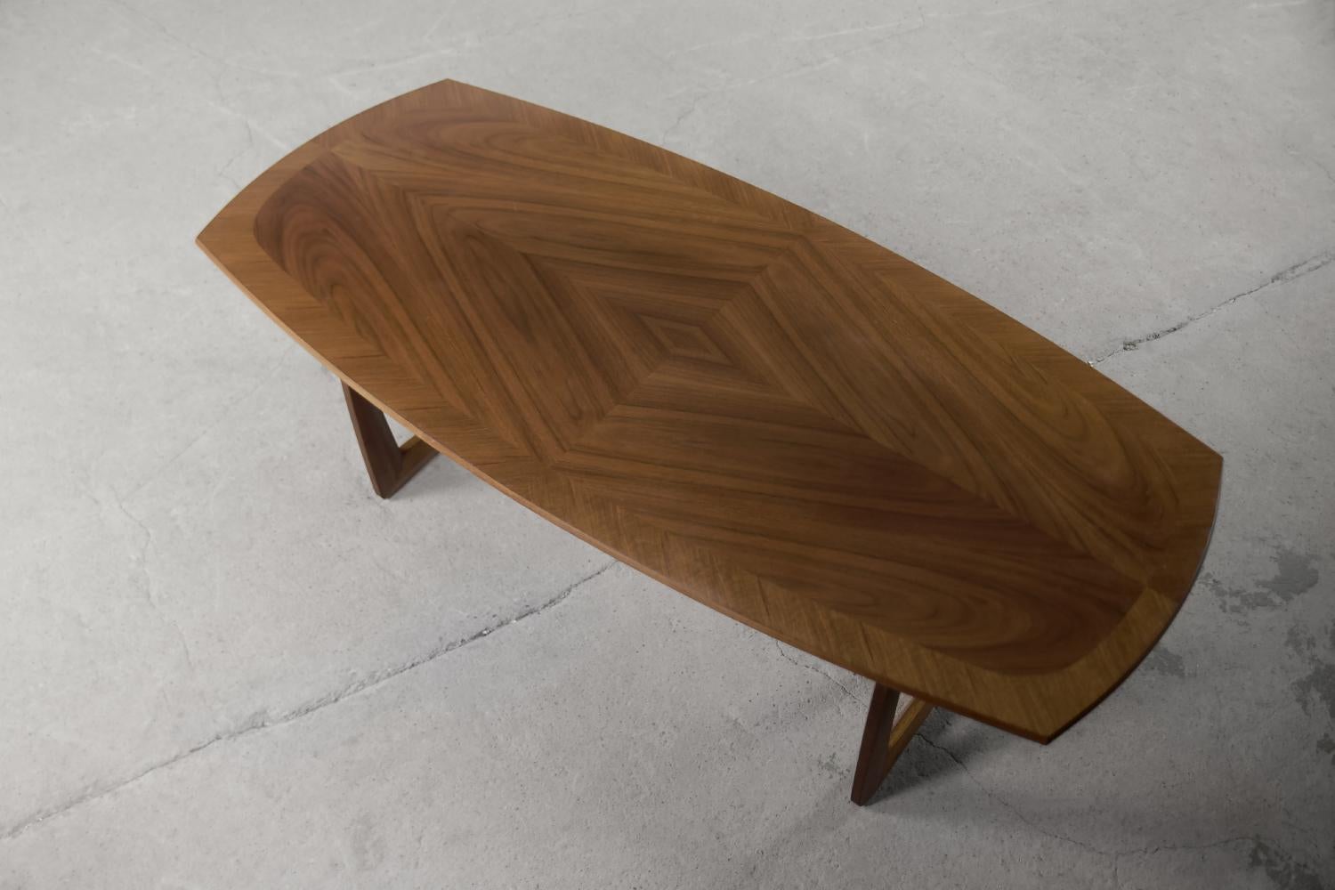 Cette table elliptique a été fabriquée par la société allemande Kondor Möbel dans les années 1960. Il était fait de bois de noyer dans une chaude nuance de brun. Les pieds de table croisés et le plateau décoratif plaqué en noyer constituent un