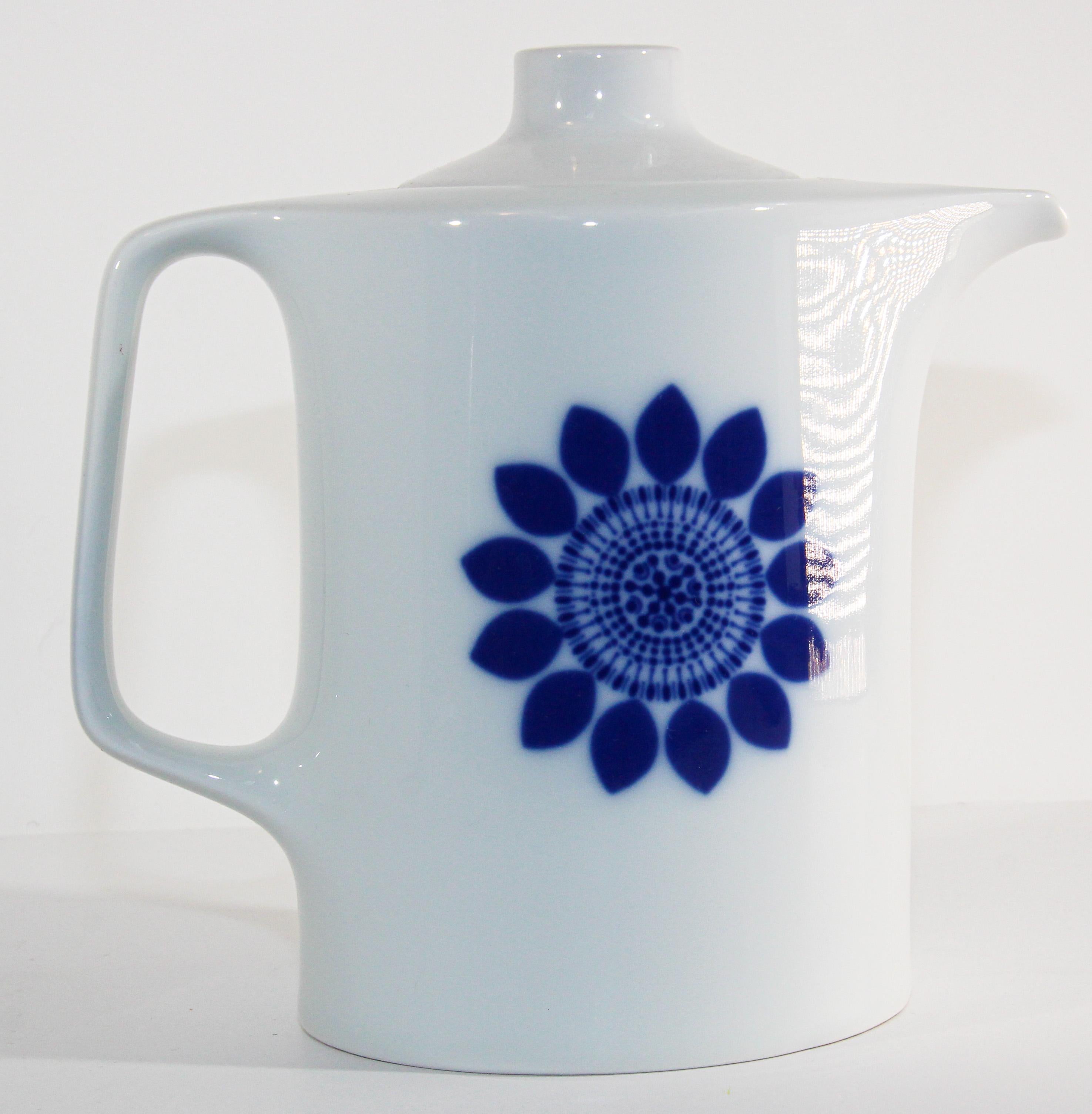 Vintage white porcelain teapot with lid and a cobalt blue stylised flower burst design on each side. 
Minimalist porcelain coffee pot or tea pot
Made in Germany, released between 1968 and 1970, by the famous designer HEINZ ENGLER.
Marked: Germany
