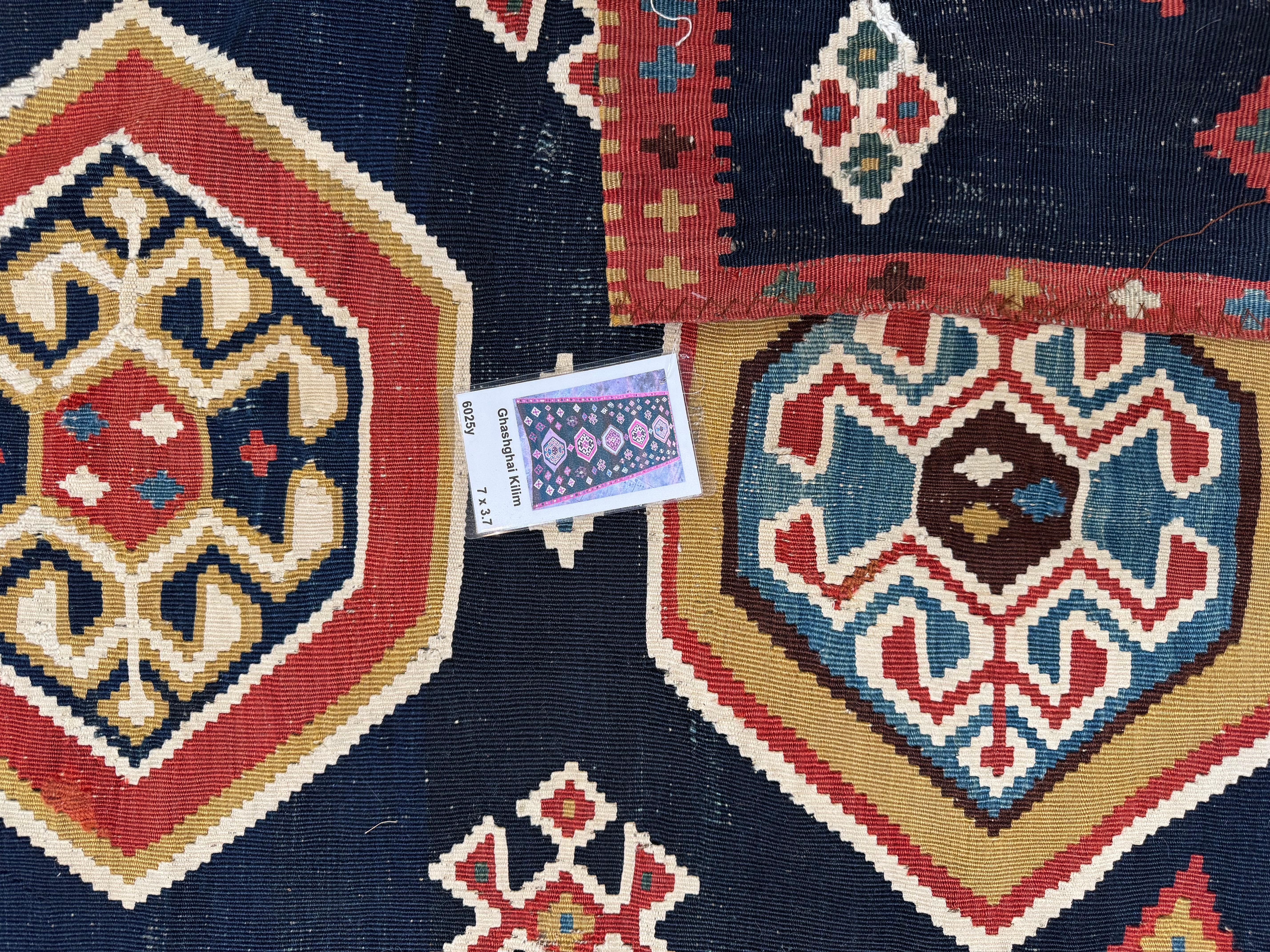 Ce superbe tapis vintage Rug & Kilim de Ghashghai est orné d'un médaillon tribal complexe sur un fond marine profond, rehaussé de nuances vibrantes de rouge, d'or, d'ivoire et de vert. Tissés à la main par les habiles nomades de Ghashghai, ses
