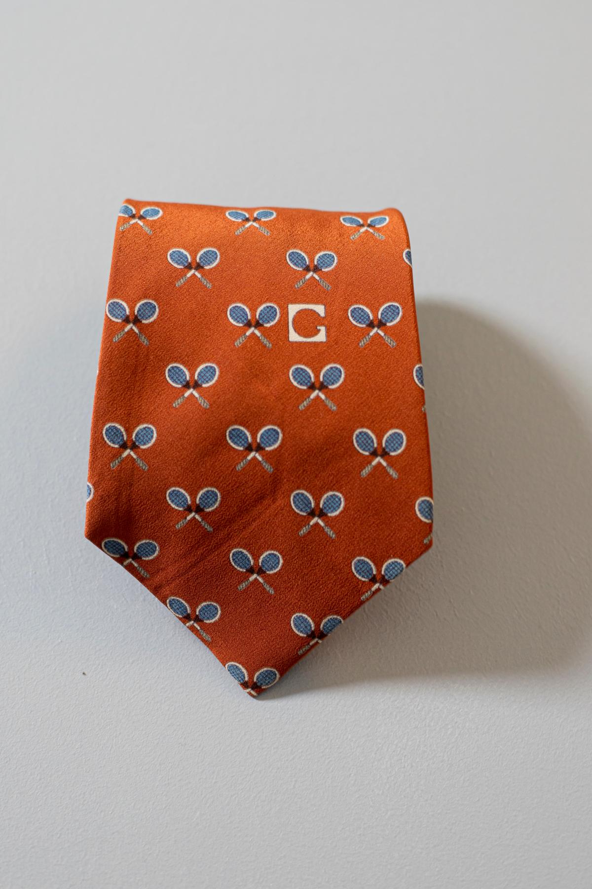 Elegant mid-century tie in silk designed by the italian stylist Gherardini. It is made of 100% silk. Decorated with small rackets on an orange background. simple but at the same time never banal, ideal for a nice Sunday brunch or a cockatil party.