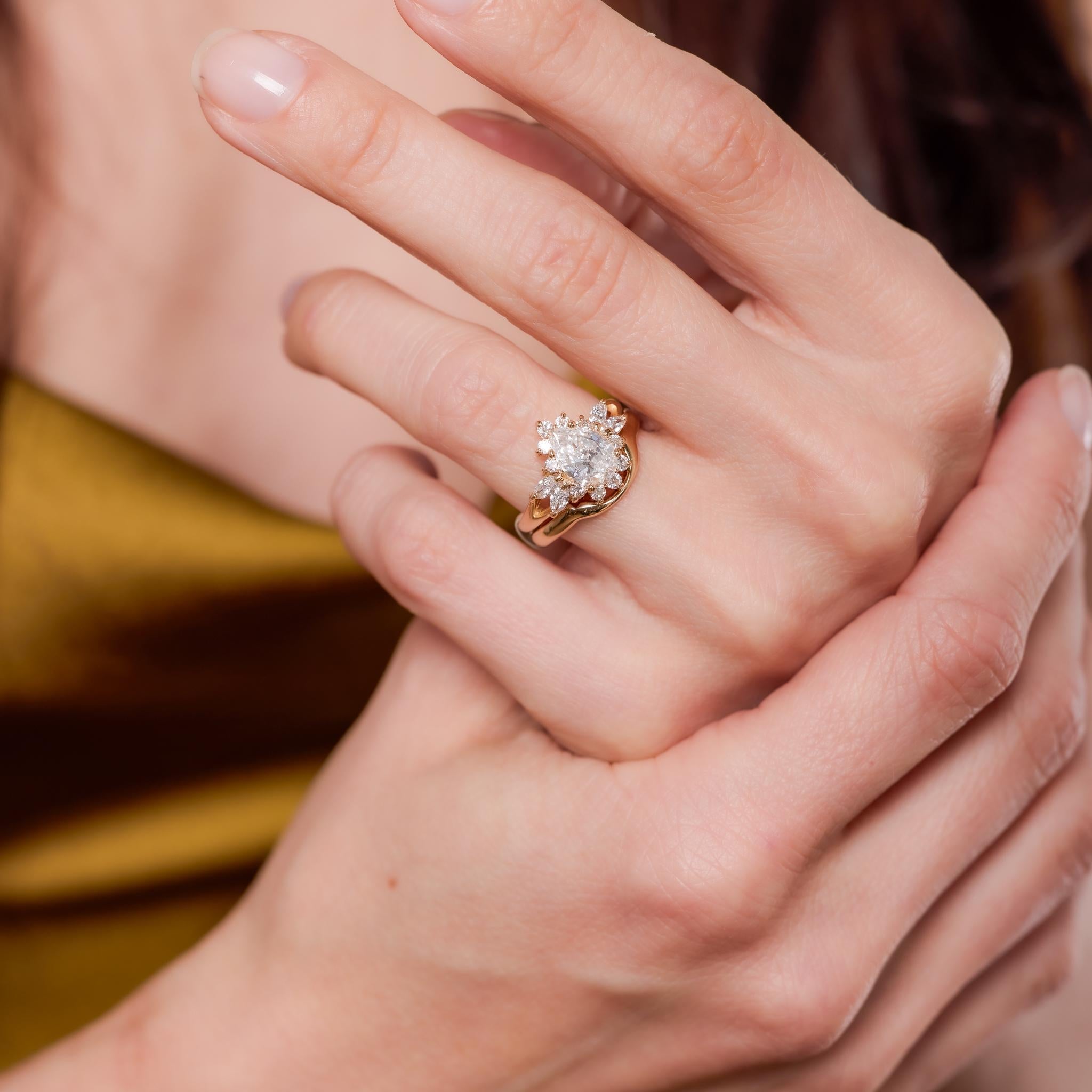 Crafted in the 1990s, this vintage ring features a GIA-certified 1.11-carat pear cut diamond, graded F color and SI1 clarity, offering exceptional brilliance and graceful shape. The center stone is framed by 4 marquise cut and 10 round brilliant cut