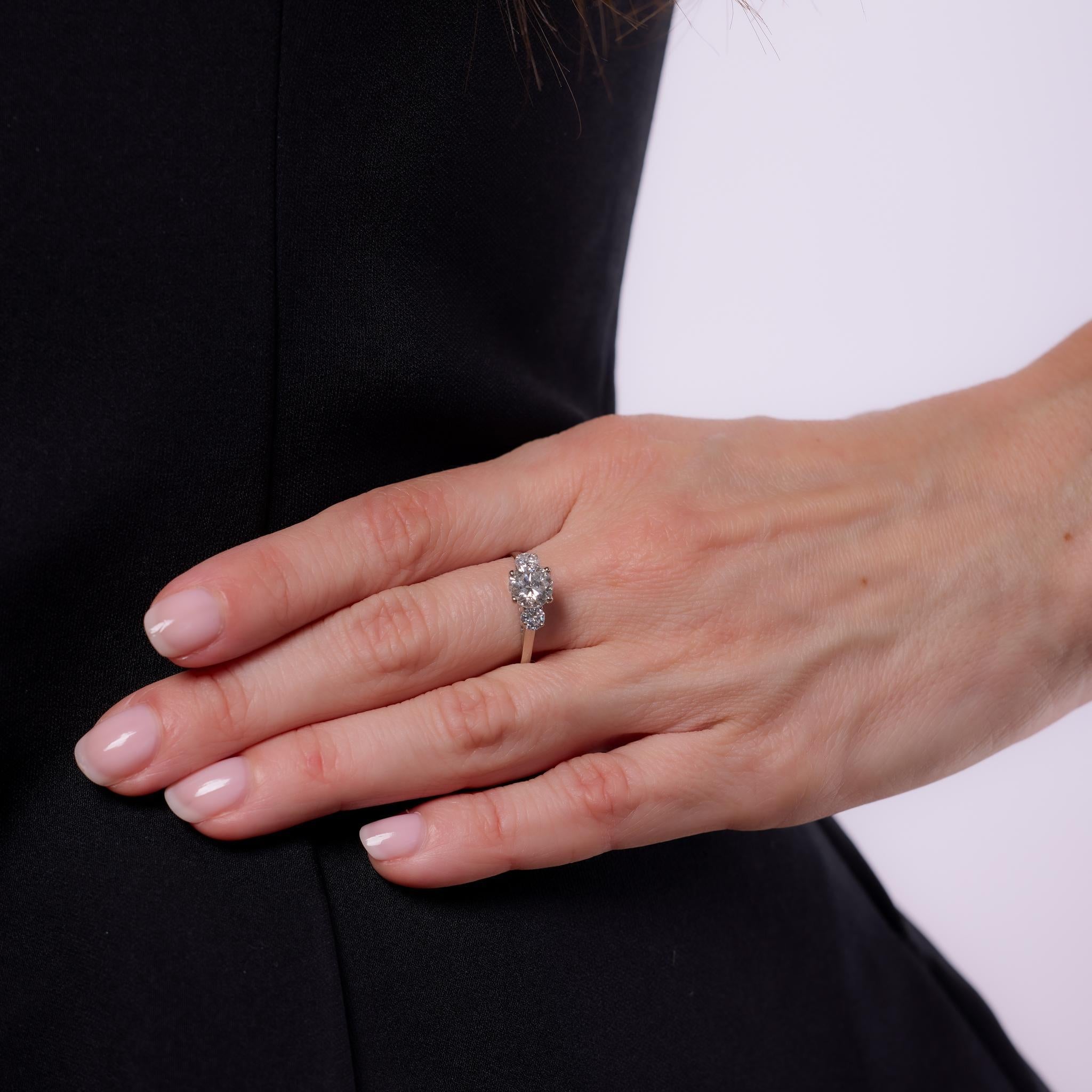 Crafted in the 1970s, this vintage engagement ring showcases a GIA-certified 1.25-carat round brilliant cut diamond, graded H color and I1 clarity. Flanked by two bright accent diamonds totaling approximately .40 carats, with E-F color and VS