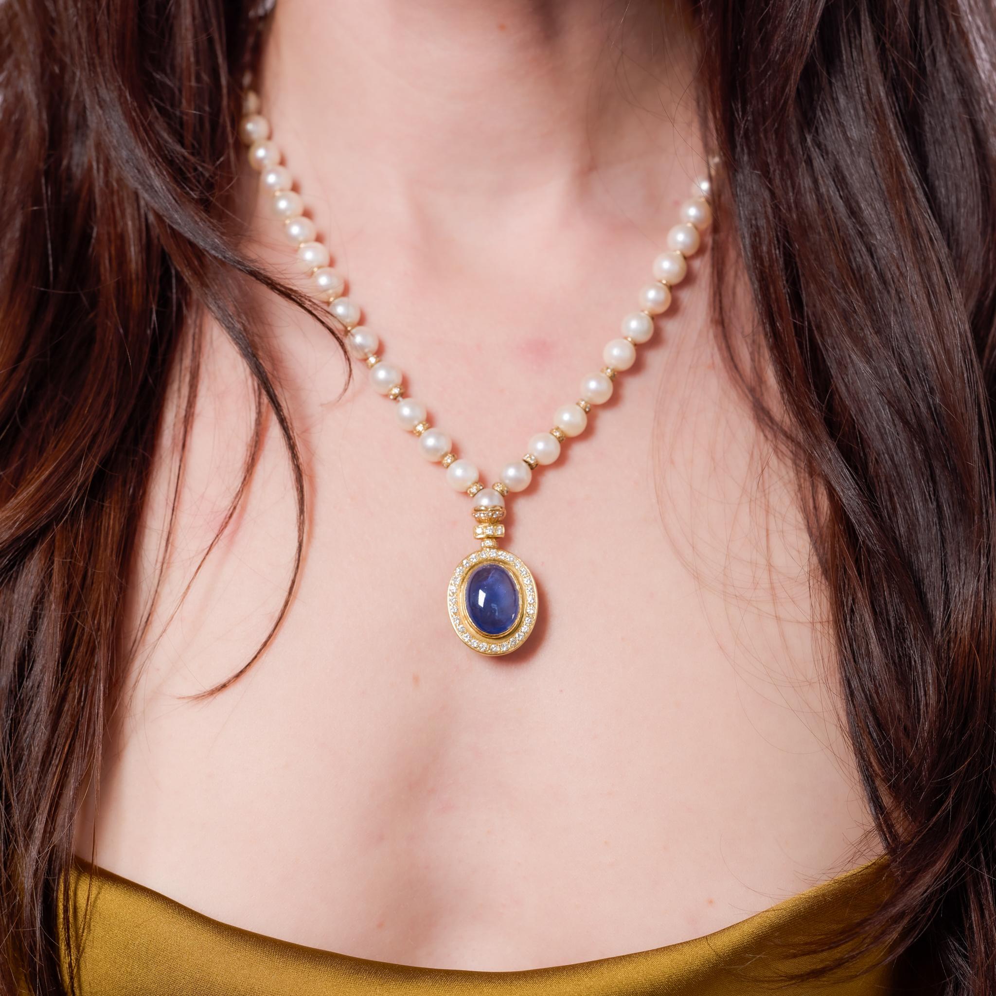 Crafted in the 1970s, this vintage 18k yellow gold necklace centers a GIA-certified 14.80-carat oval double cabochon cut blue sapphire from Ceylon, treated with heat to enhance its rich color. Surrounding the sapphire are 112 round brilliant cut