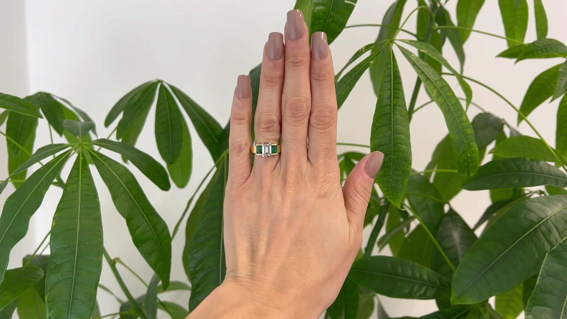 One Vintage GIA 1.53 Carats Emerald Cut Diamond Emerald 18k Yellow Gold Three Stone Ring. Featuring one GIA emerald cut diamond of 1.53 carats, accompanied with GIA #1288301172 stating the diamond is E color, SI1 clarity. Accented by two rectangular