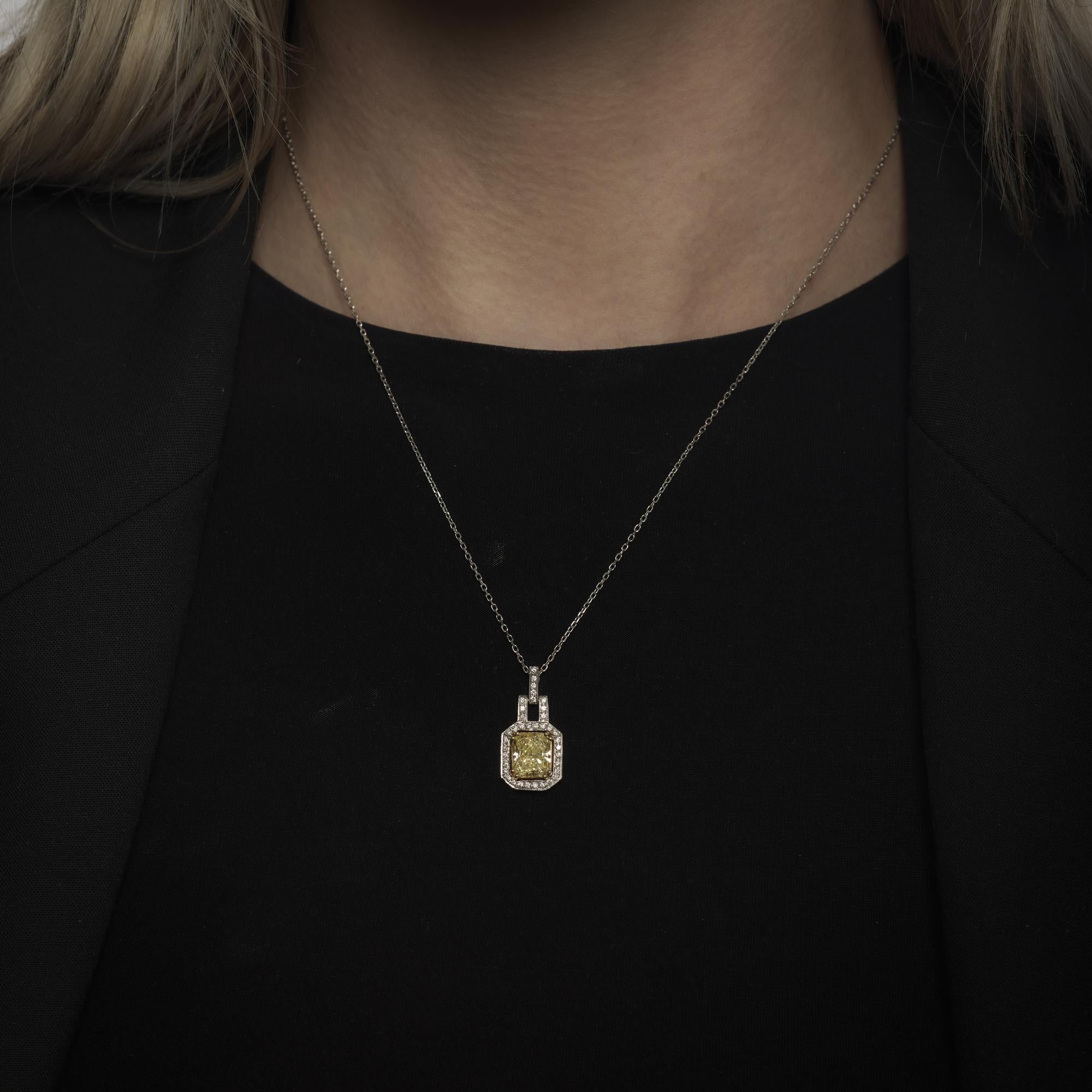 Un vibrante diamante de corte radiante amarillo fantasía de 2,20 quilates constituye el punto focal de este collar vintage de oro blanco de 14 quilates, enmarcado por treinta y ocho diamantes brillantes redondos que suman aproximadamente 0,40