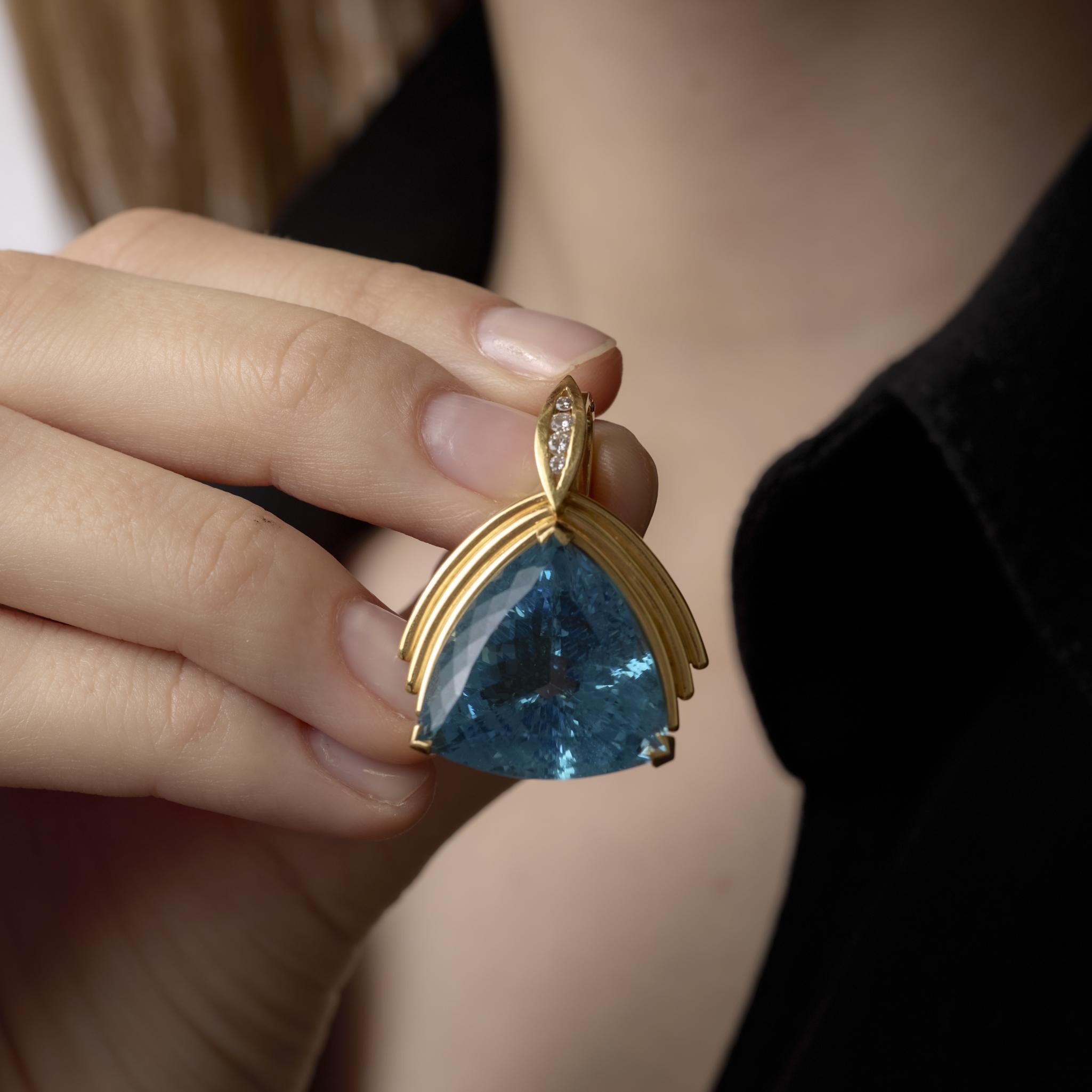 Ce pendentif vintage en or jaune 18 carats rayonne avec une superbe aigue-marine triangulaire de 27 carats encadrée de diamants étincelants, capturant le luxe intemporel et l'art raffiné.