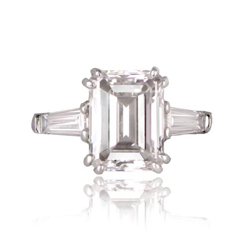 An exquisite vintage engagement ring showcasing a vibrant GIA-certified 3.07-carat emerald-cut diamond with D color and VS1 clarity. The center diamond is elegantly complemented by two tapered baguette diamonds. Crafted in 18k white gold, this