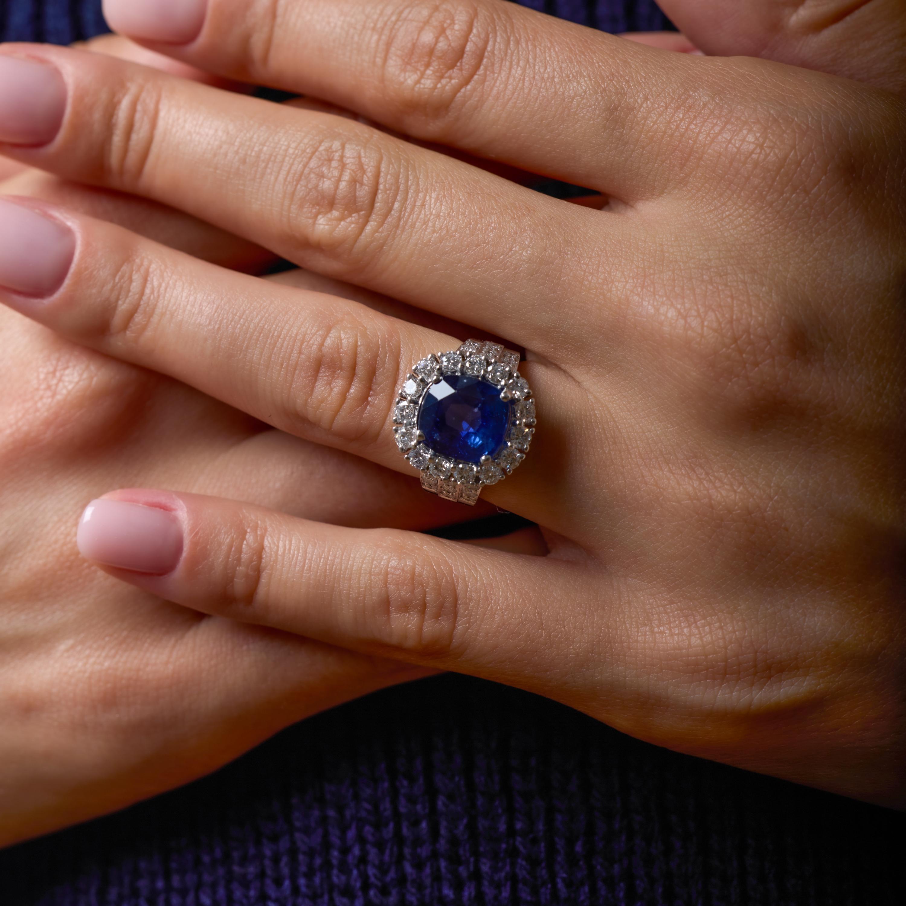 Questo straordinario anello vintage a grappolo ruota attorno a uno zaffiro di Ceylon da 4,97 carati, il cui vivido colore blu è illuminato da un'opulenta aureola di raffinati diamanti di colore F e purezza VS. Le generose proporzioni dello zaffiro