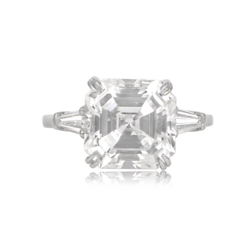 A stunning vintage engagement ring featuring a 5.02-carat Asscher-cut diamond. The prong-set center diamond is set in hand-crafted platinum, flanked by two baguette-cut diamonds. It comes with GIA certification and boasts 5.02 carats, F color, and