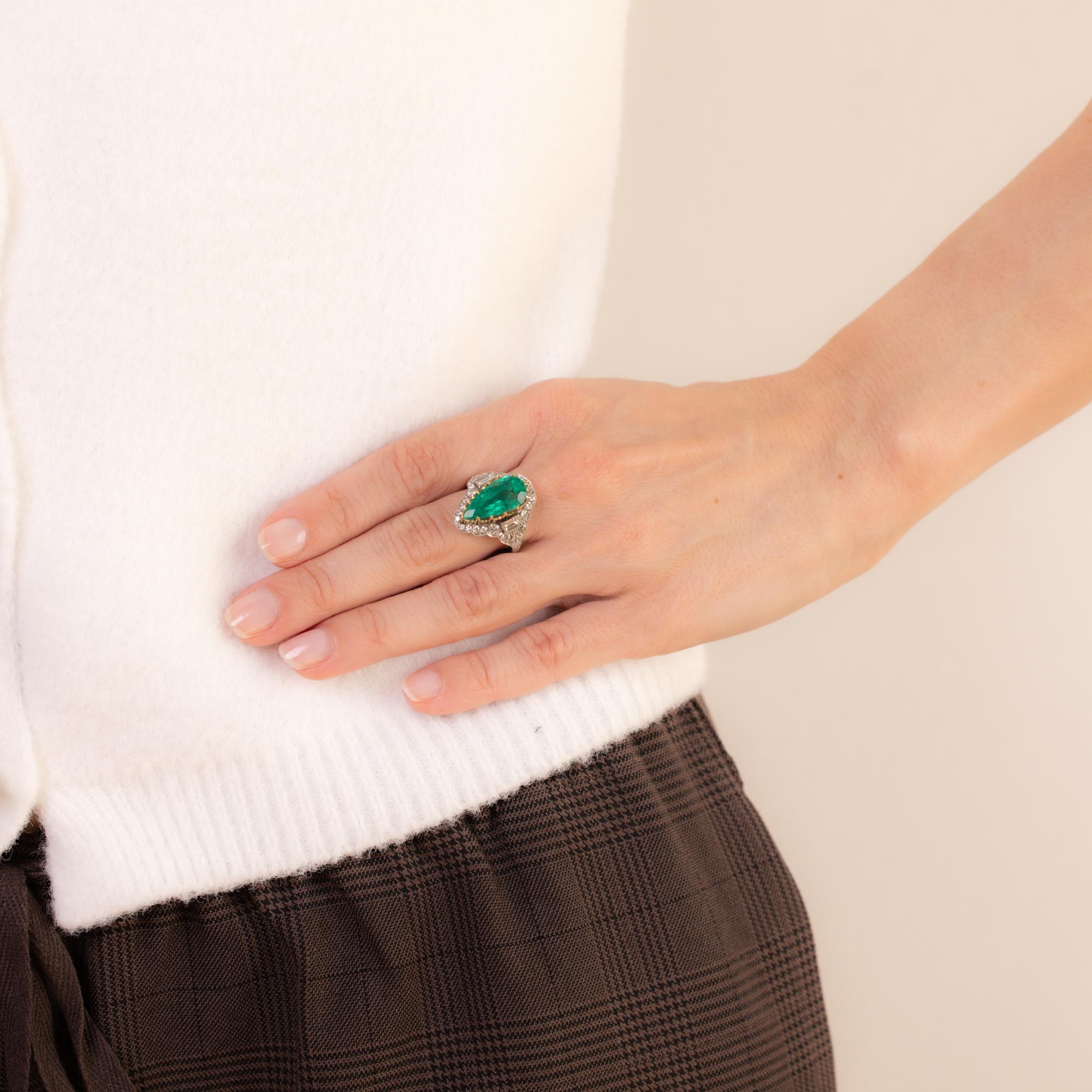 This vintage platinum ring features a GIA-certified 6.20-carat pear-cut Colombian emerald, F1 treatment, accented by 33 round brilliant and baguette-cut diamonds totaling approximately 1 carat, E-F color, VS-SI clarity. Stone weight engraved. Circa