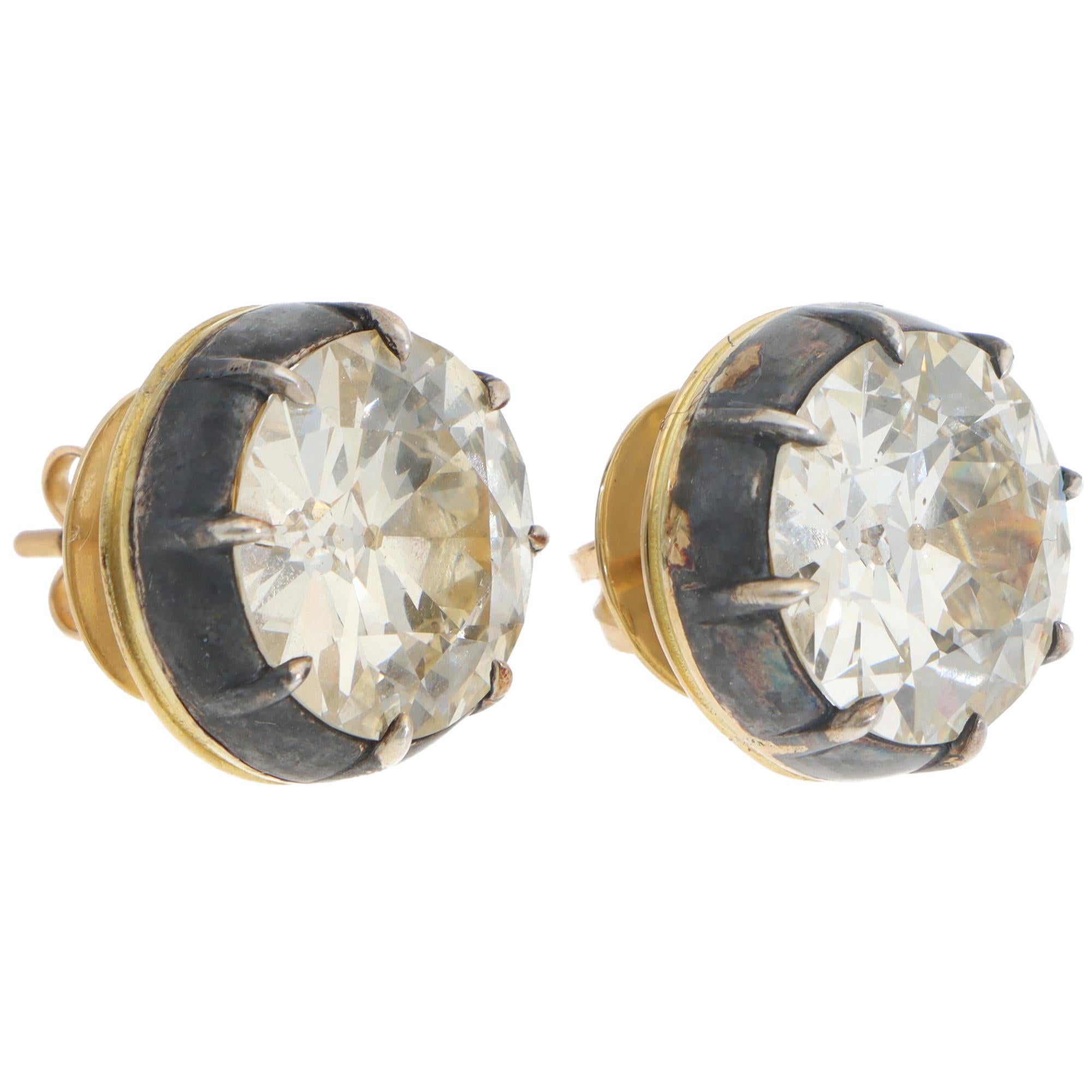 A breathtaking pair of vintage old European-cut diamond stud earrings set in silver and 18k yellow gold.

Each earring solely features a sizeable old European-cut diamond, which is set securely in a Georgian cut-down setting. The silver on gold