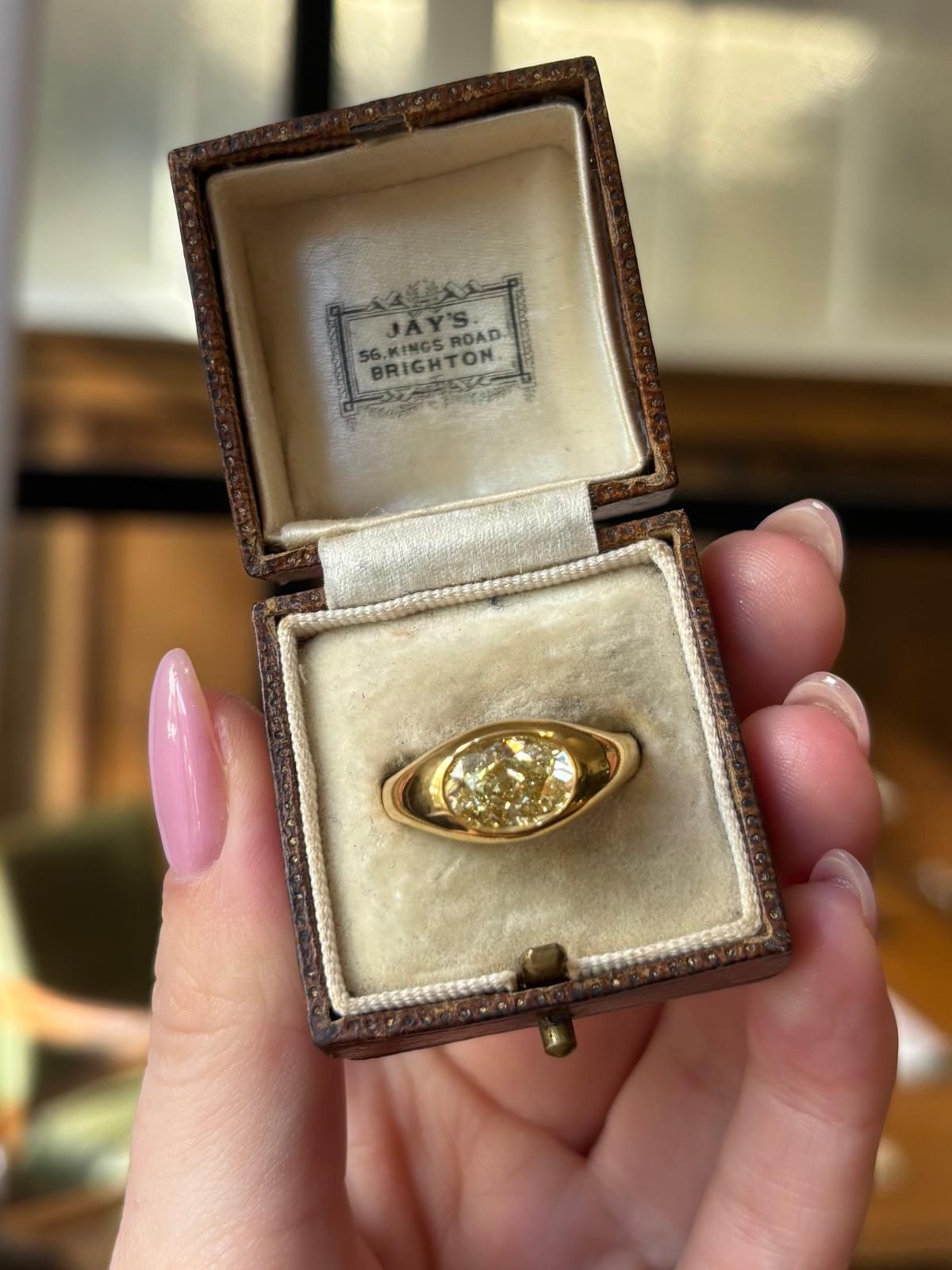 A sparkly vintage GIA certified Fancy Yellow oval diamond bezel set ring in 18k yellow gold. 

The ring is solely set with a GIA certified Fancy Yellow oval cut diamond, set east-west in a rub over solid yellow gold bezel setting.

Due to the