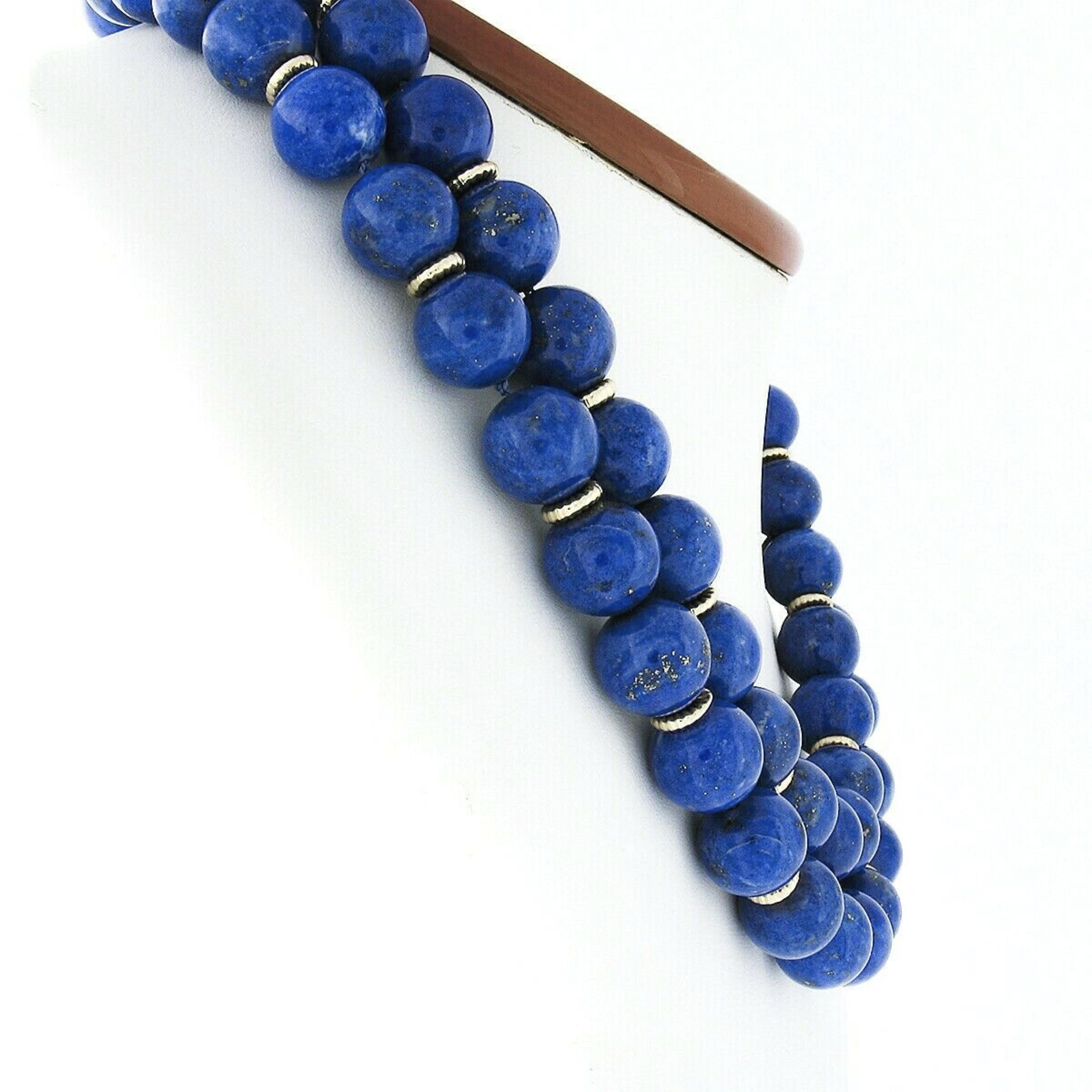This gorgeous vintage dual strand statement necklace features 63 genuine lapis lazuli beads that are neatly strung throughout both strands alternating with solid 14k yellow gold textured spacers. The fine lapis are GIA certified (2 were randomly