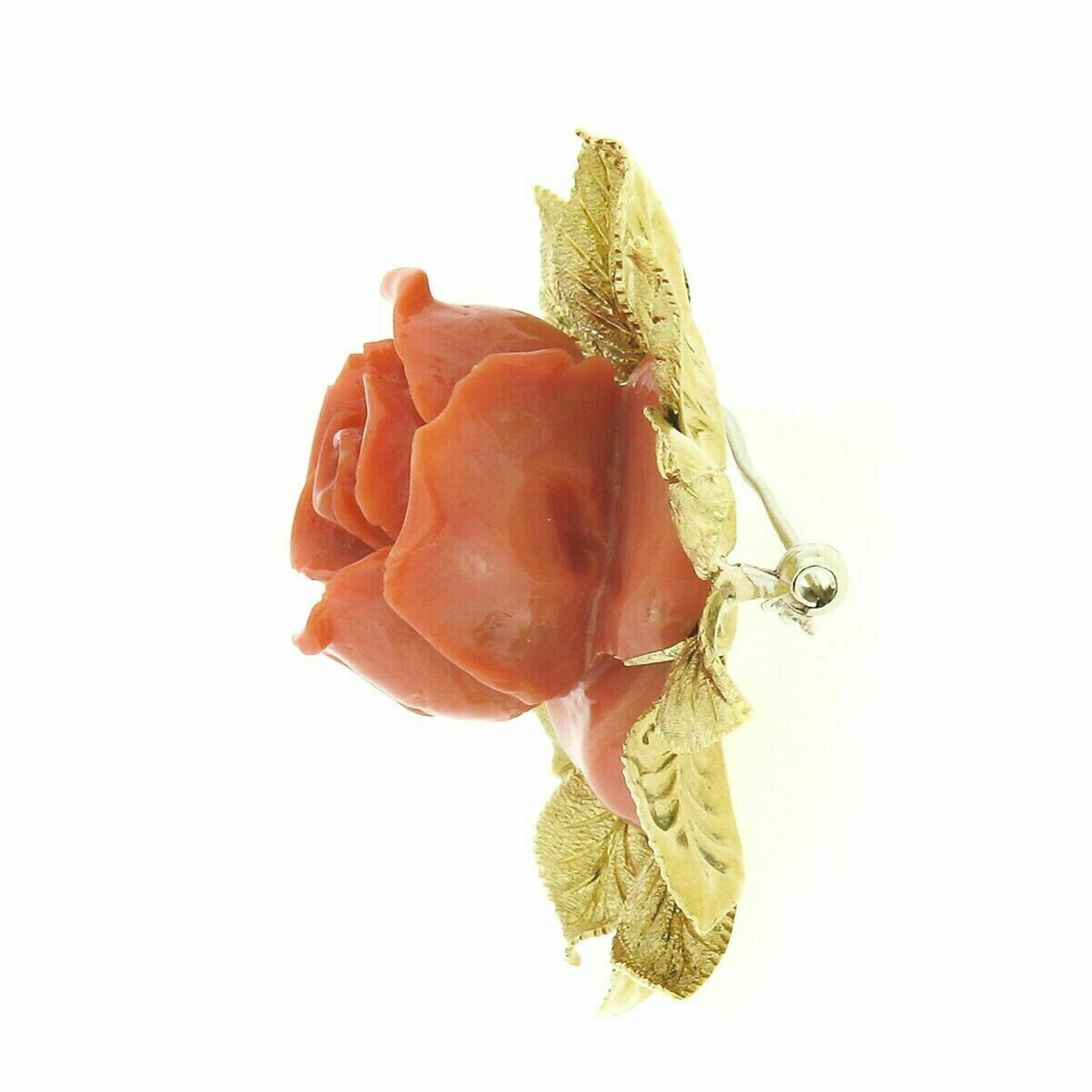 This large and very well-made vintage brooch was crafted from solid 18k yellow gold. It features a beautiful, GIA certified, natural coral set into an incredibly detailed and textured leaf border frame. The coral is a reddish-orange color and is