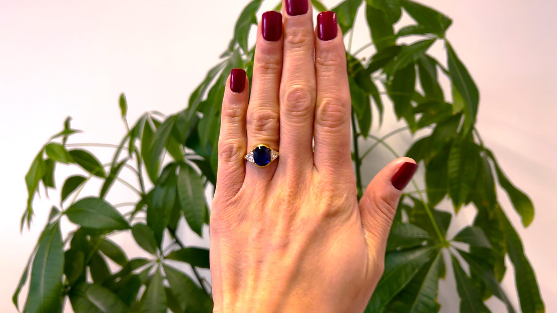 One Vintage GIA Thai 4.46 Carat Sapphire and Diamond 18k Yellow Gold Three Stone Ring. Featuring one oval mixed cut sapphire weighing 4.46 carats, accompanied with GIA #2235134968 stating the sapphire is of Thai origin. Accented by two trillion cut