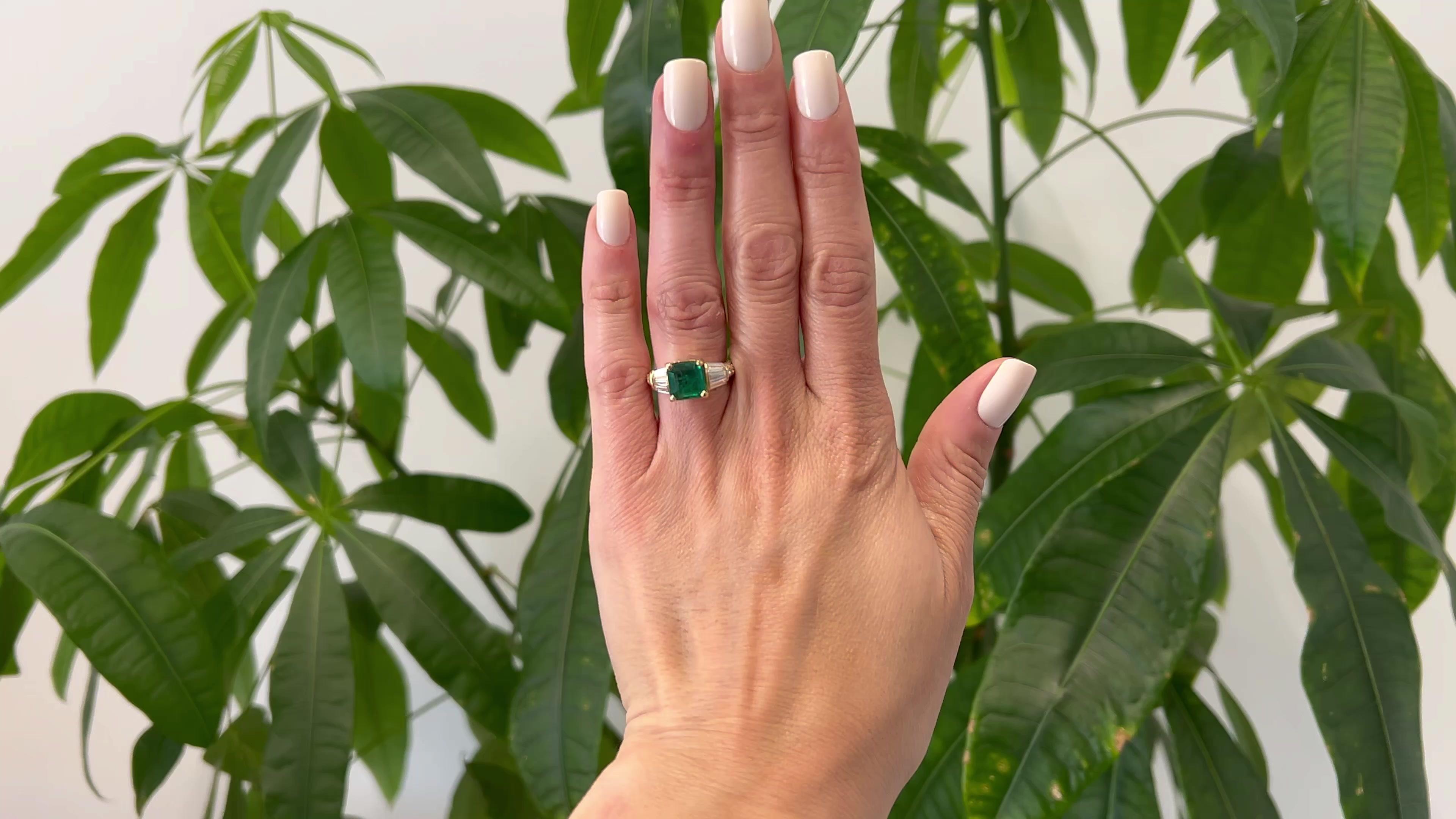 One Vintage GIA Zambian Emerald and Diamond 18K Yellow Gold Ring. Featuring one GIA octagonal step cut emerald weighing 3.61 carats, accompanied with GIA #2235012352 stating the emerald is of Zambian origin. Accented by six tapered baguette cut