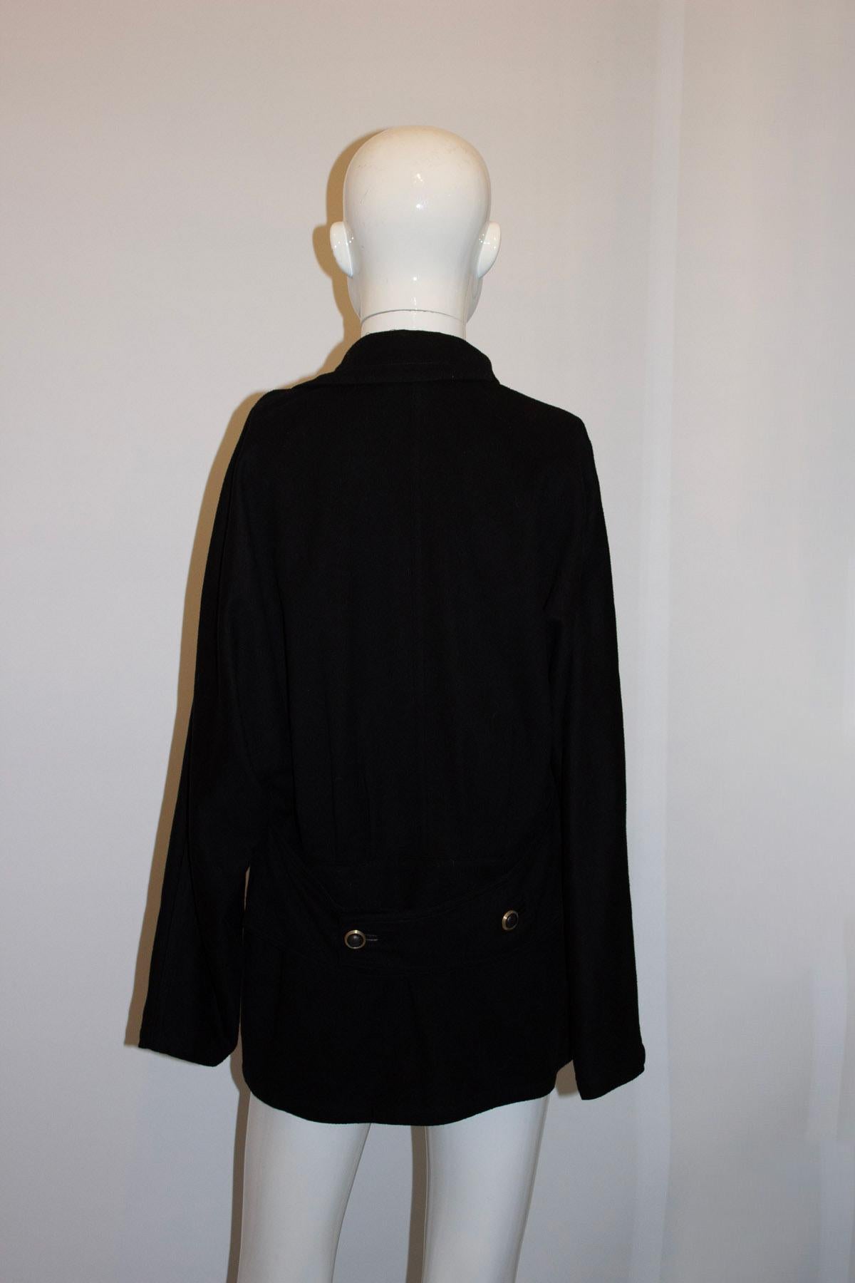 A great vintage jacket by Gianni Versace. In black wool , the jacket has a cross over front with two lower pockets , and one breast pocket. It has an interesting collar , one side being different from the other. It has pleats at the back and back